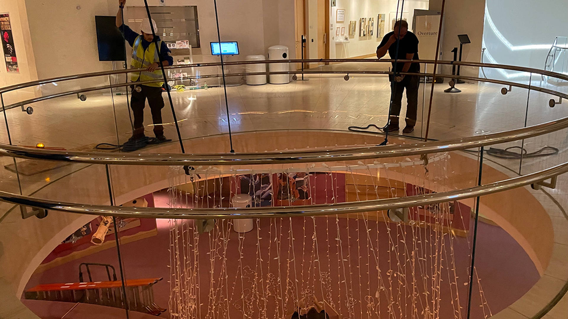 Overture tech staff suspending a halo of lights in Rotunda Lobby