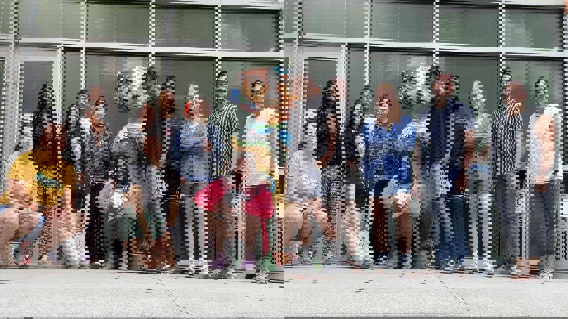 Students posing for a photo together in front of a bucky statue.
