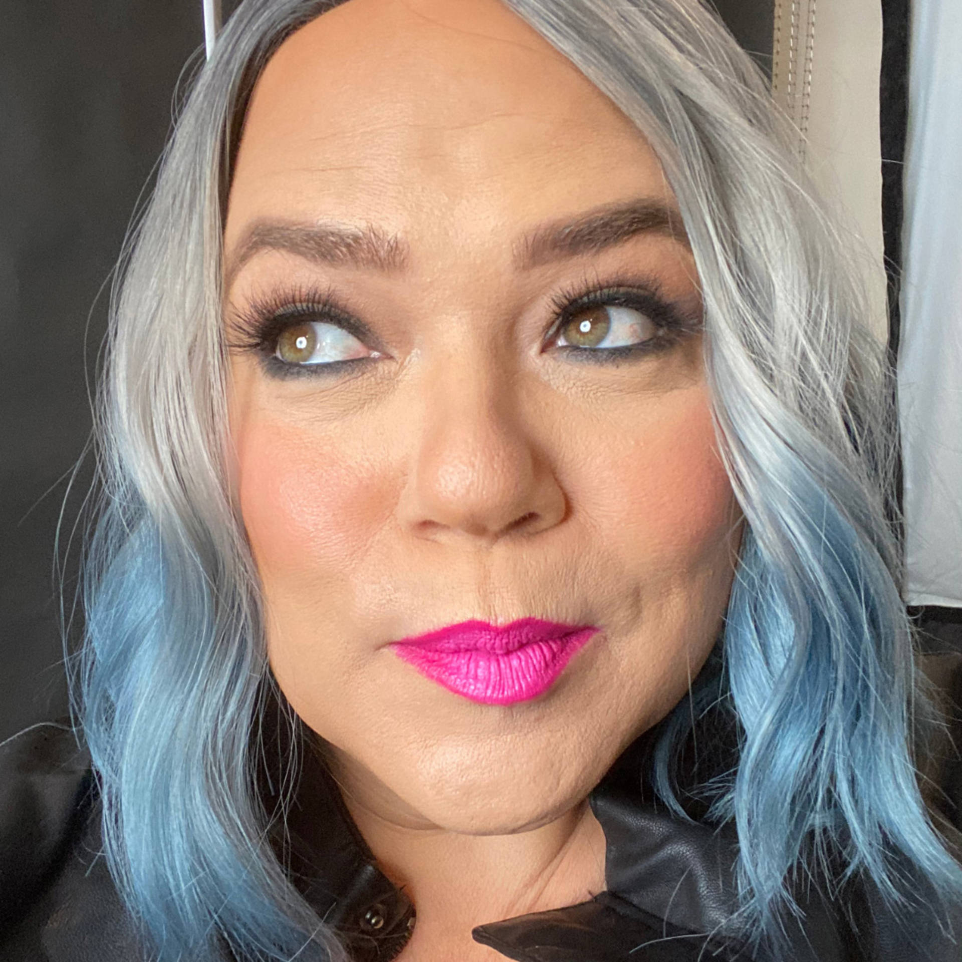 Close up image of a person with medium complexion, long silver and blue hair, hazel eyes and pink lipstick.