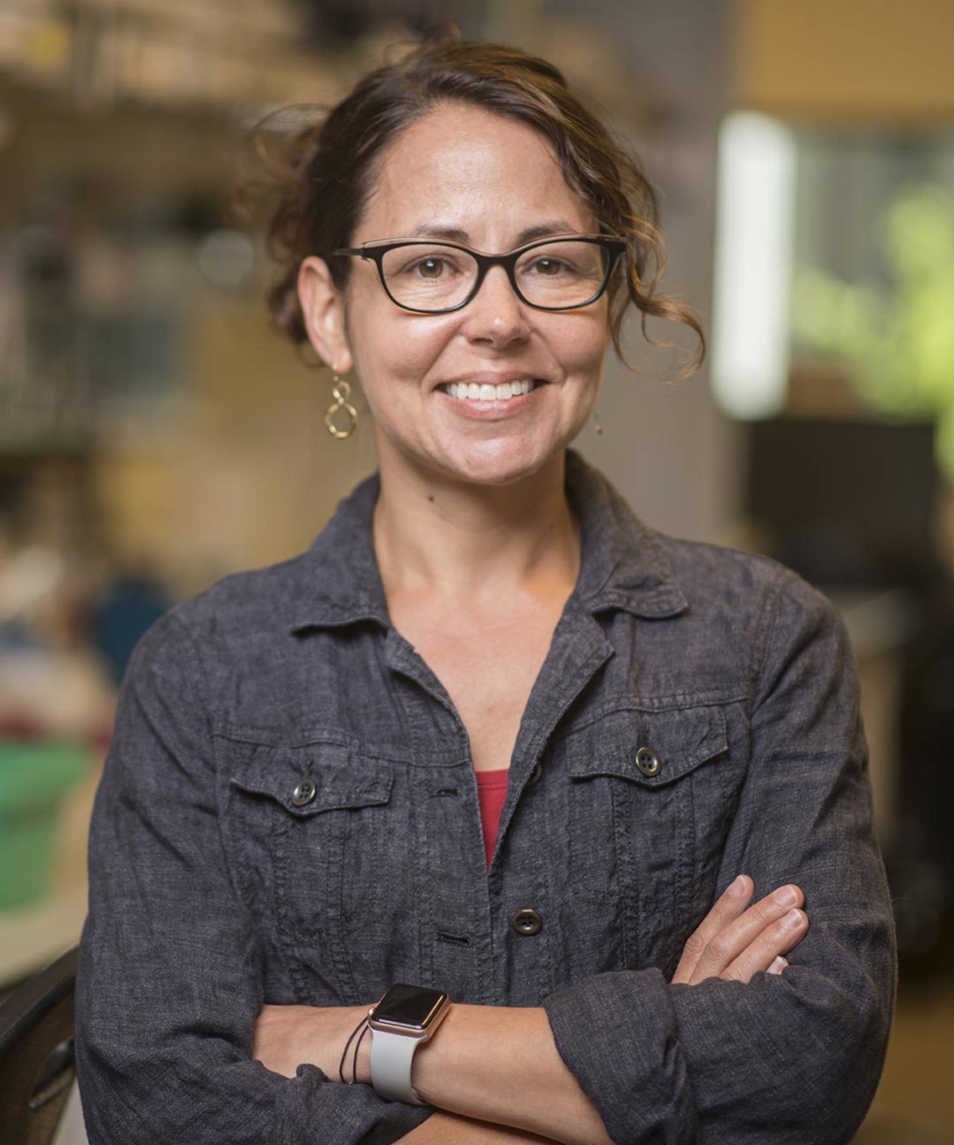 Headshot of Beth Shapiro. A white woman with brown curly hair and black framed glasses.