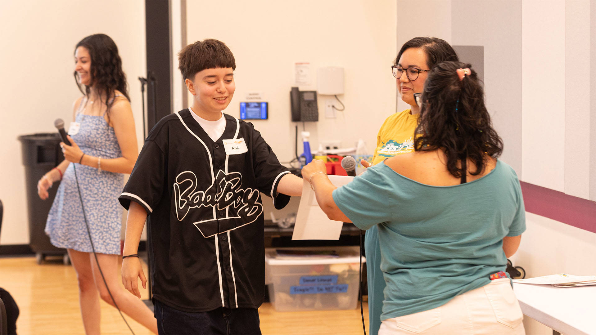 A student accepts a piece of paper from an older woman in a teal top.