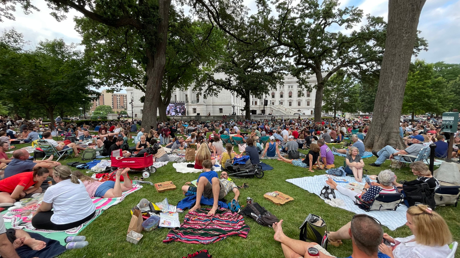 Concert goers lounge on colorful blanks on the Wisconsin capitol lawn.
