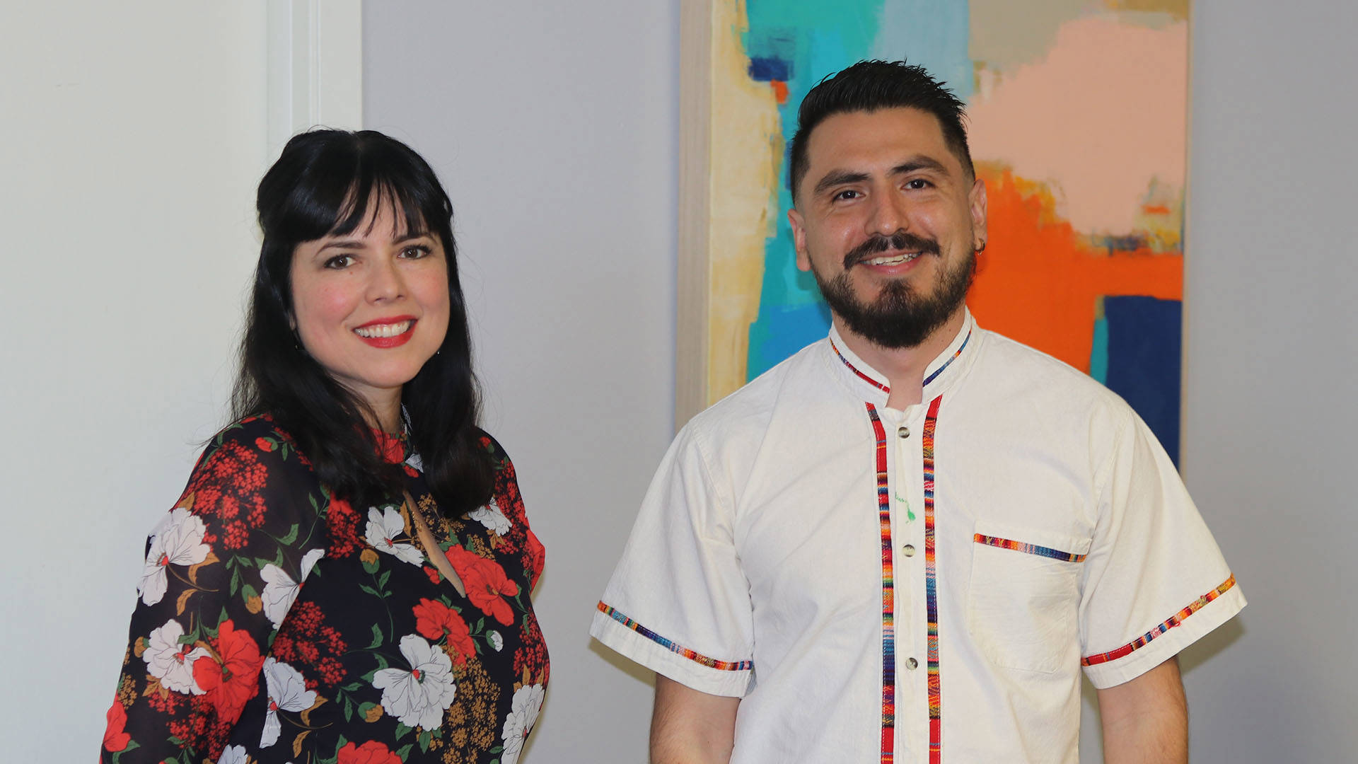 A man and a woman smile and pose for a picture. They both have dark hair and brown eyes.