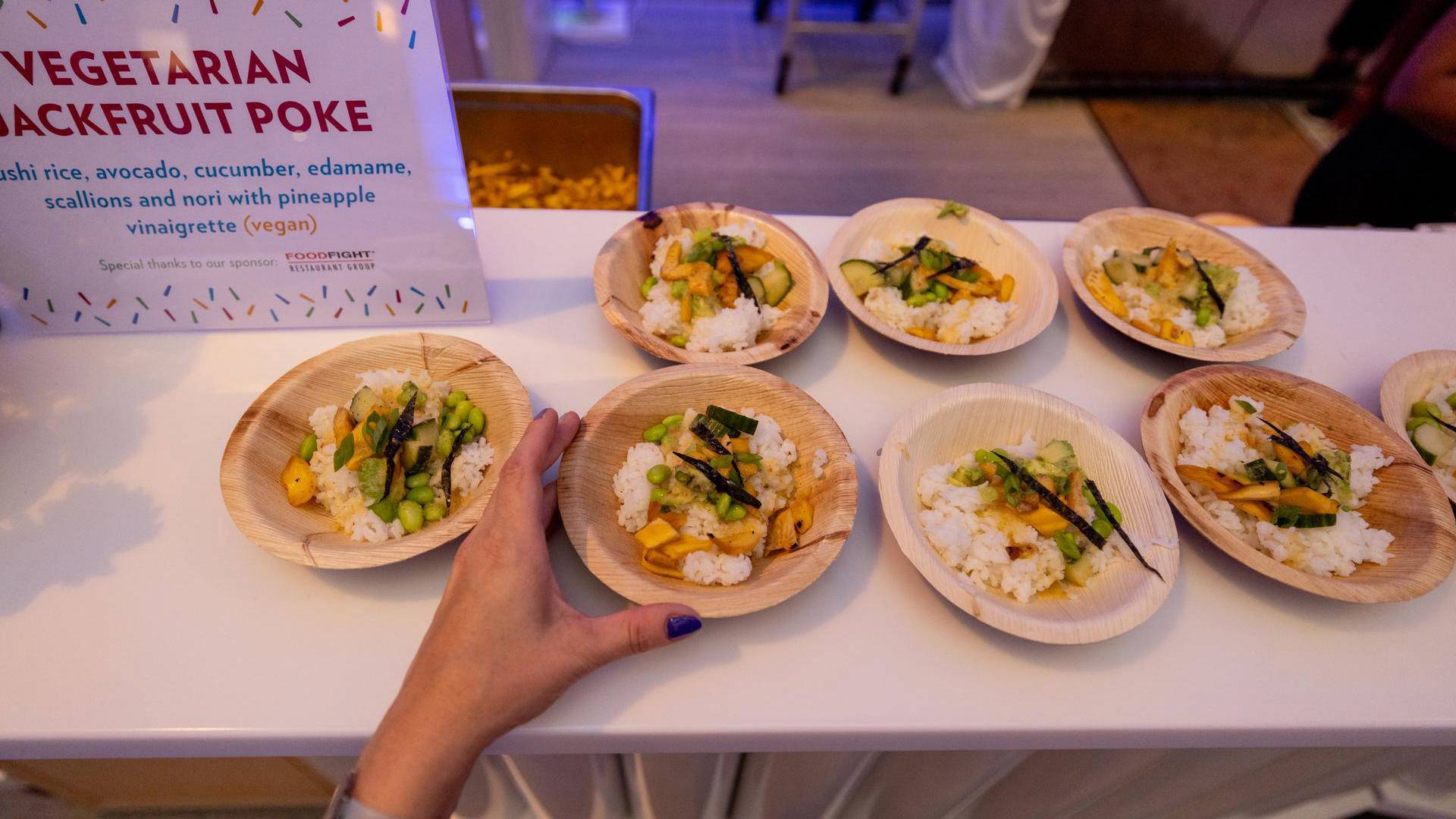 Wooden plates with vegetables and rice on a white table.