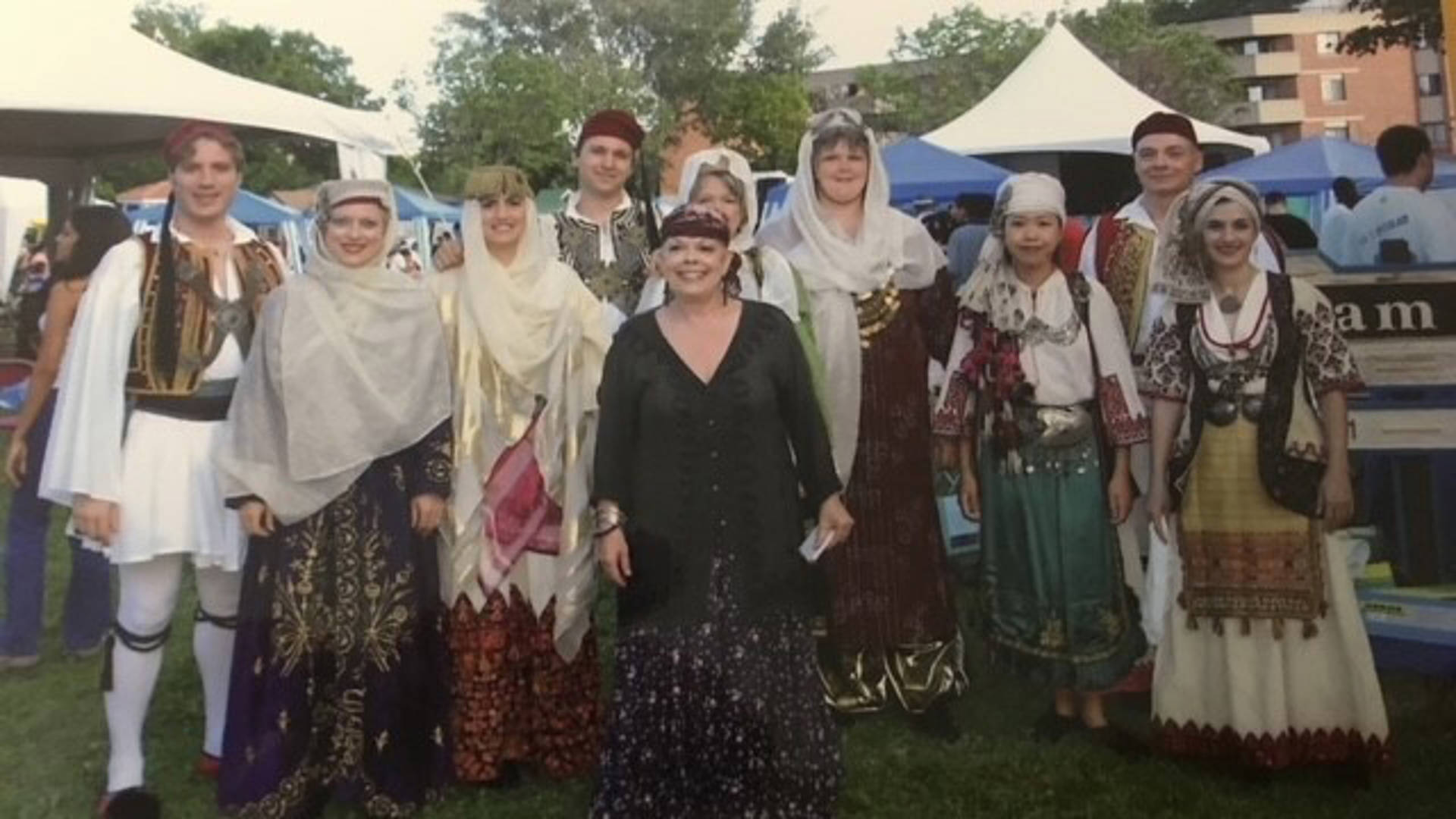 A group of dancers posing in colorful traditional Greek dance outfits posing for a photo.