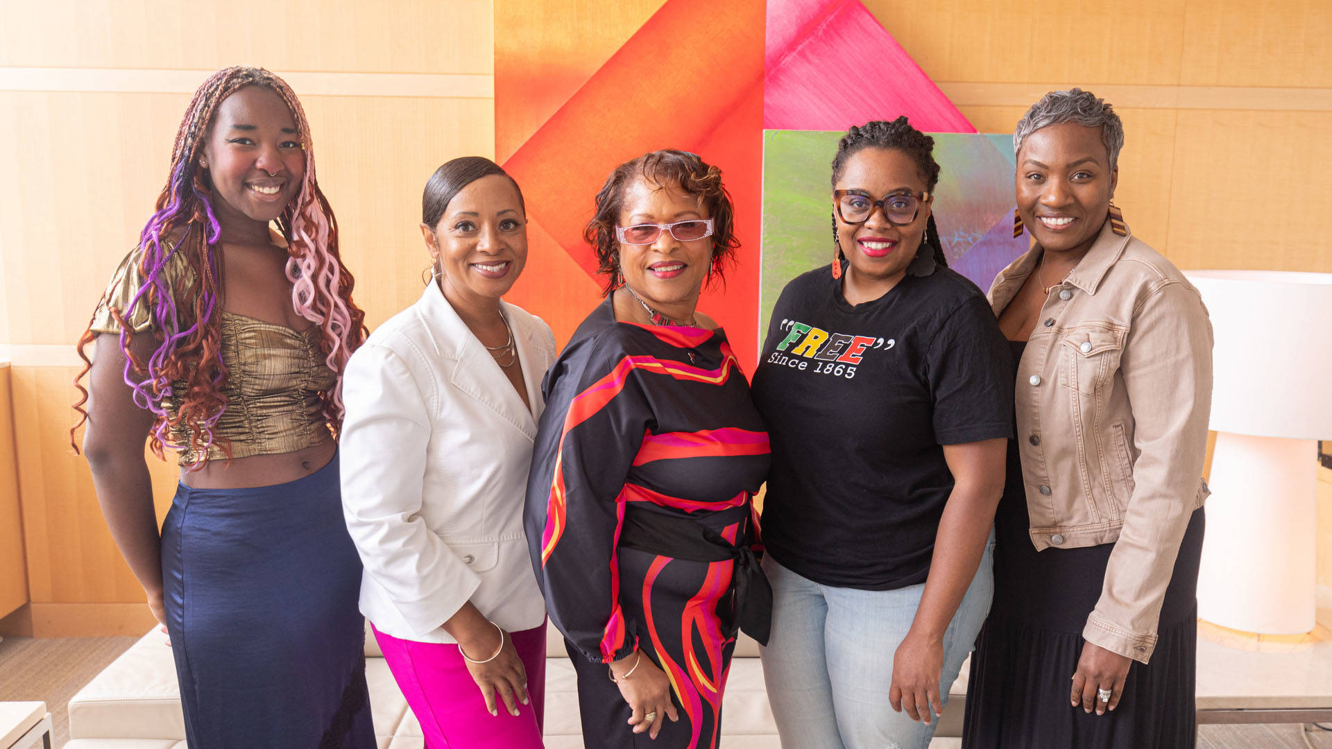 Five african american women stand together smiling for a photo.