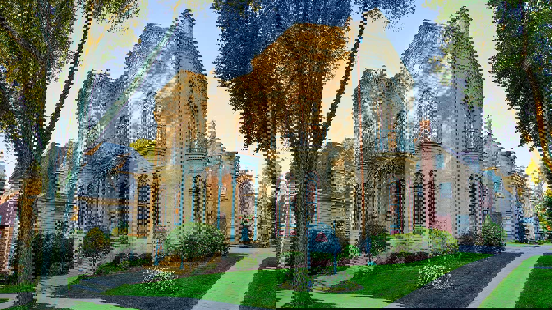 A large ornate beige building with balconies and tall windows. It has a historic look to it and has immaculate gardening and landscaping.