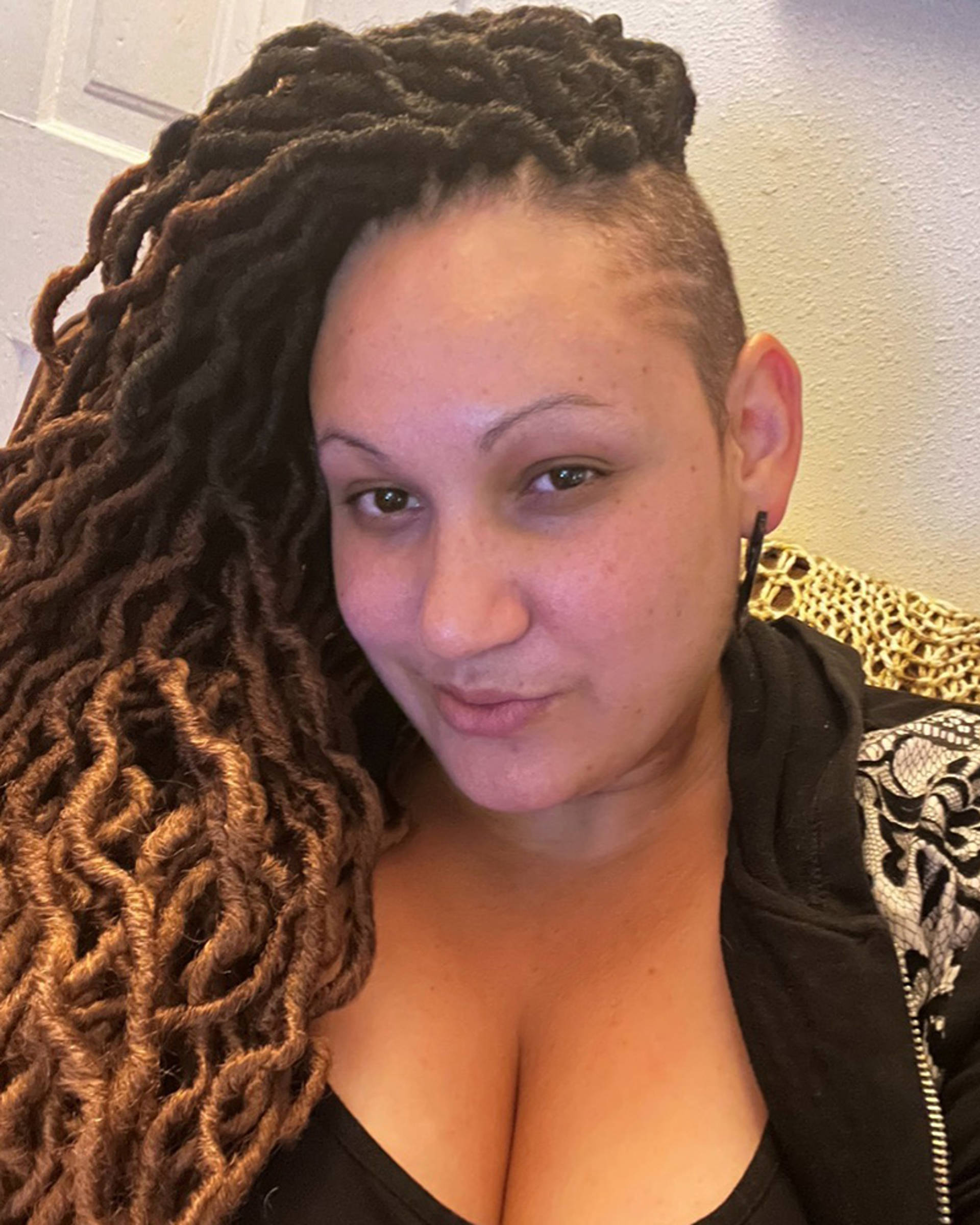 Headhot of a woman with medium complexions, brown eyes, and long brown hair. She has a black hoodie on.