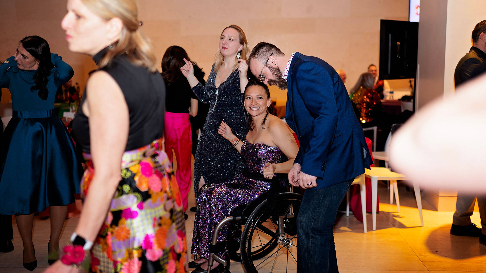 A woman in a wheelchair smiles and is enjoying moving to music with others around her.
