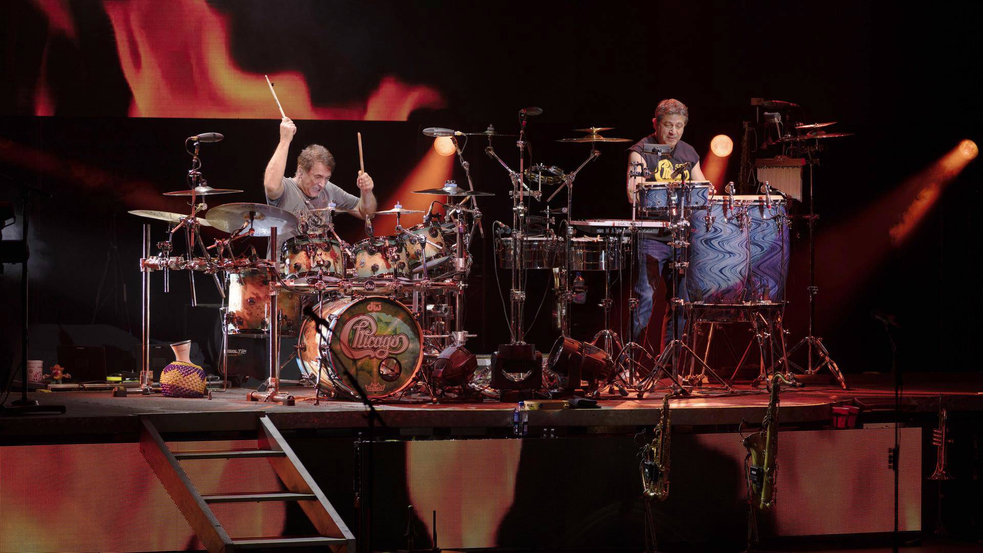 Two men on a stage playing drums.
