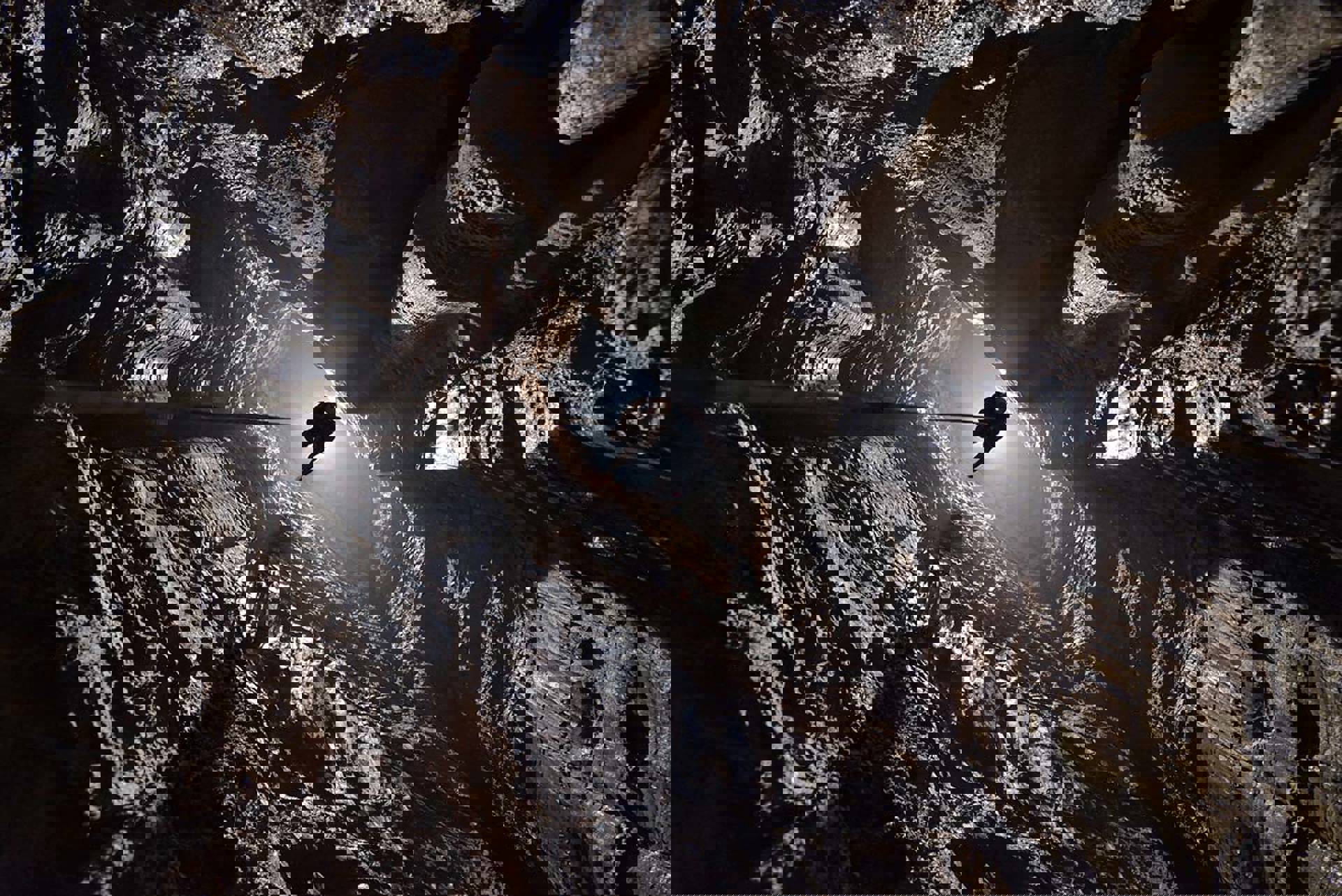 A climber hanging from a rope in a giant cave