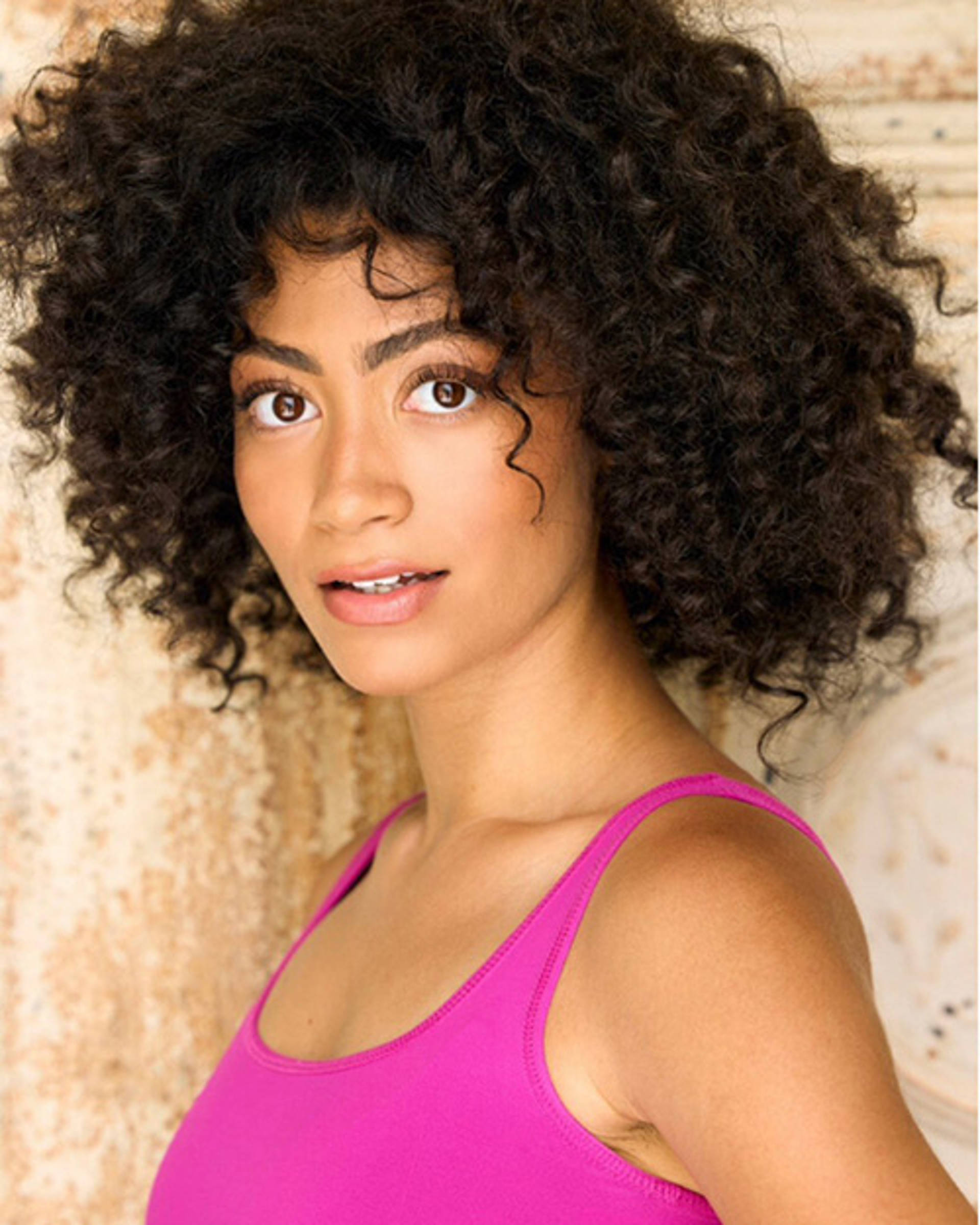 Headshot of an African American Woman with medium length curly hair and brown eyes.