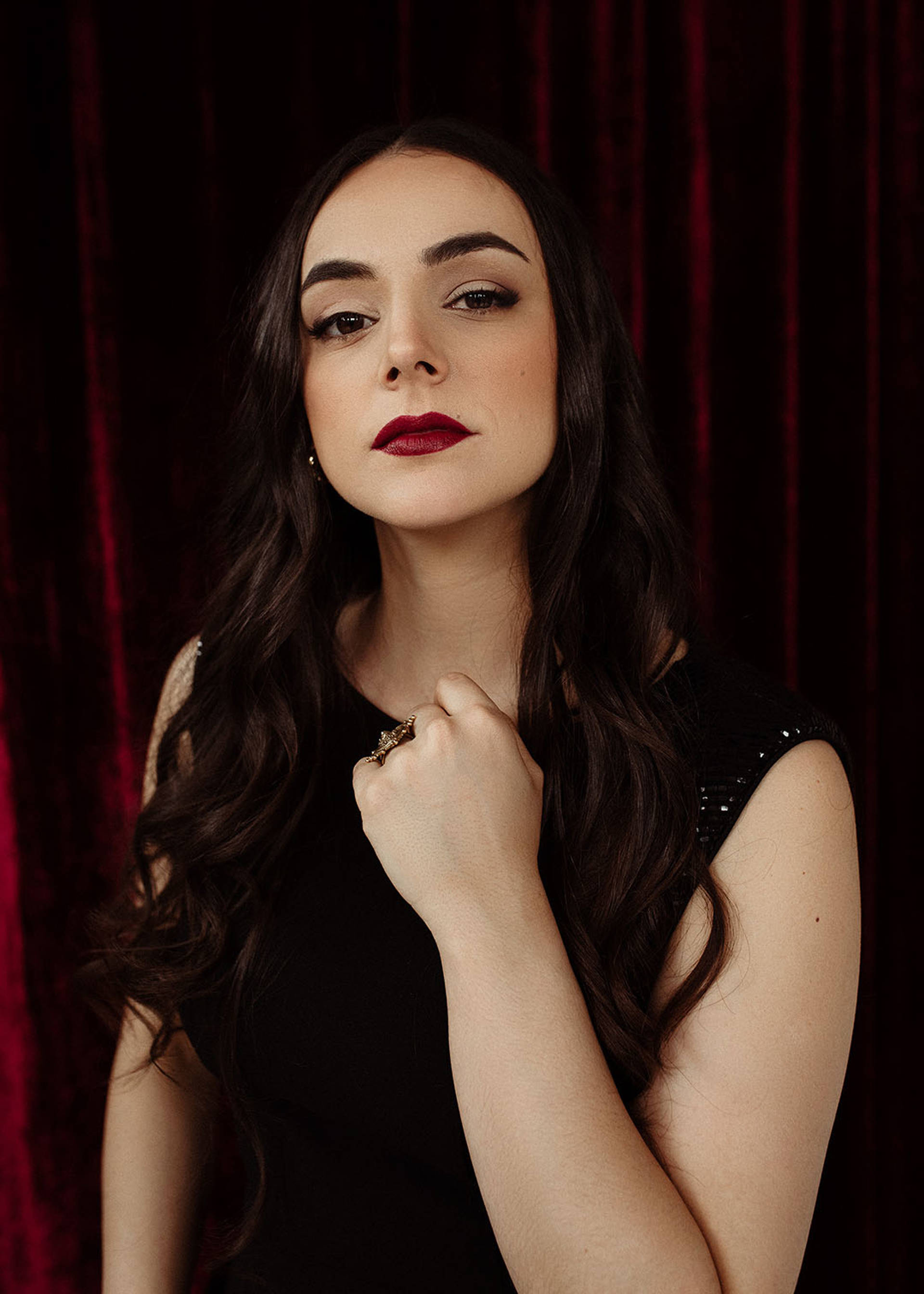 A young woman with light complexion, brown hair, long dark hair, and a dark dress.