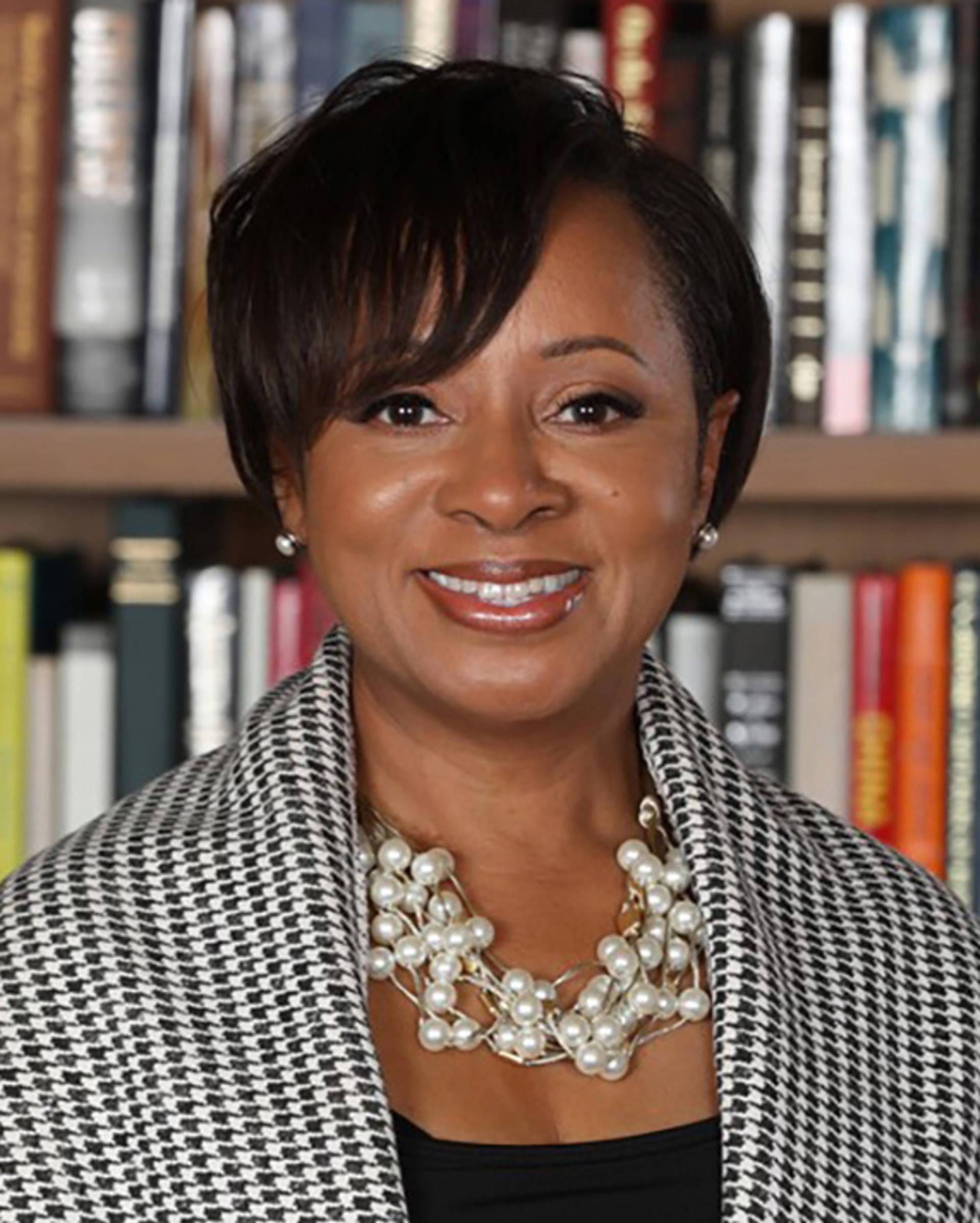 A headshot of a smiling middleaged African American woman with short  hair, and a black and white shawl on