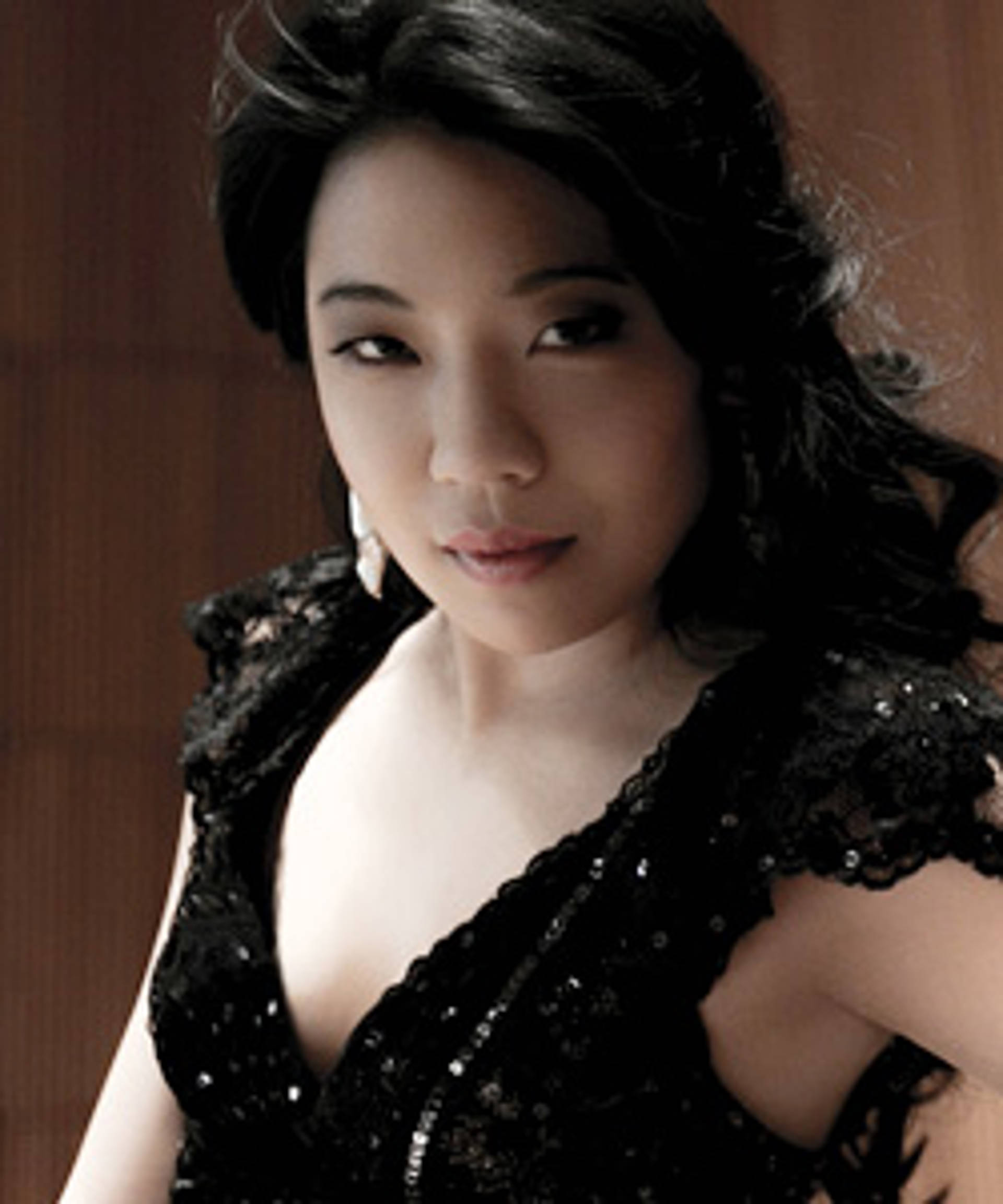 Headshot of a woman with medium tone skin and long dark hair in a black dress.