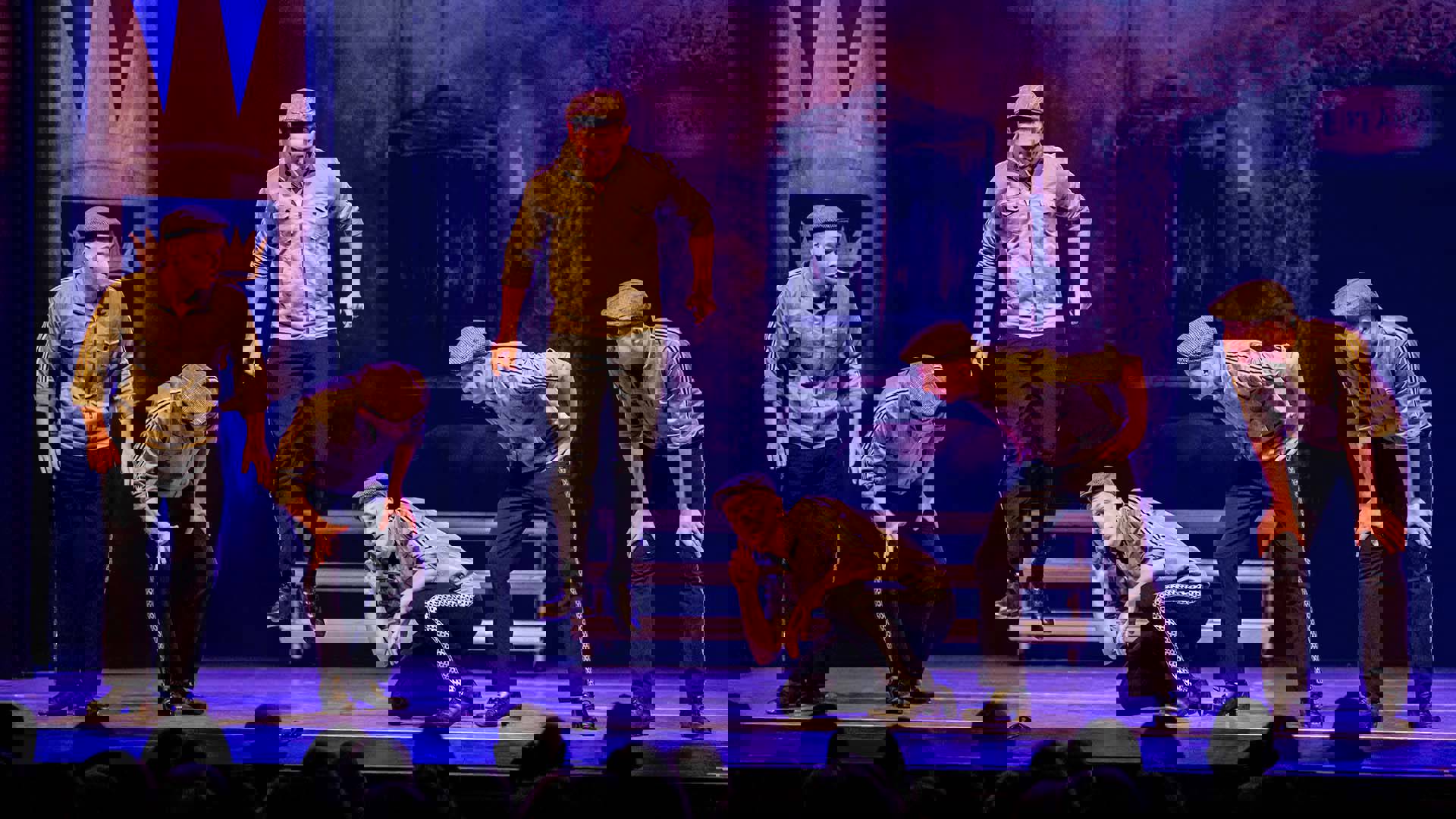 A group of Irish dancers in tan and blackeoutfits performing on stage.