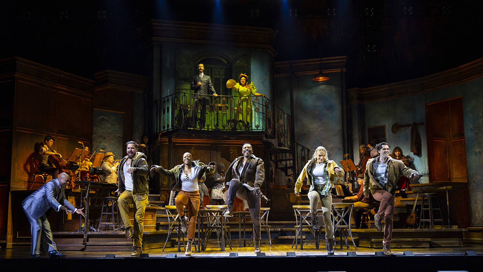 The cast of Hadestown performing on stage. They are dancing in unison.