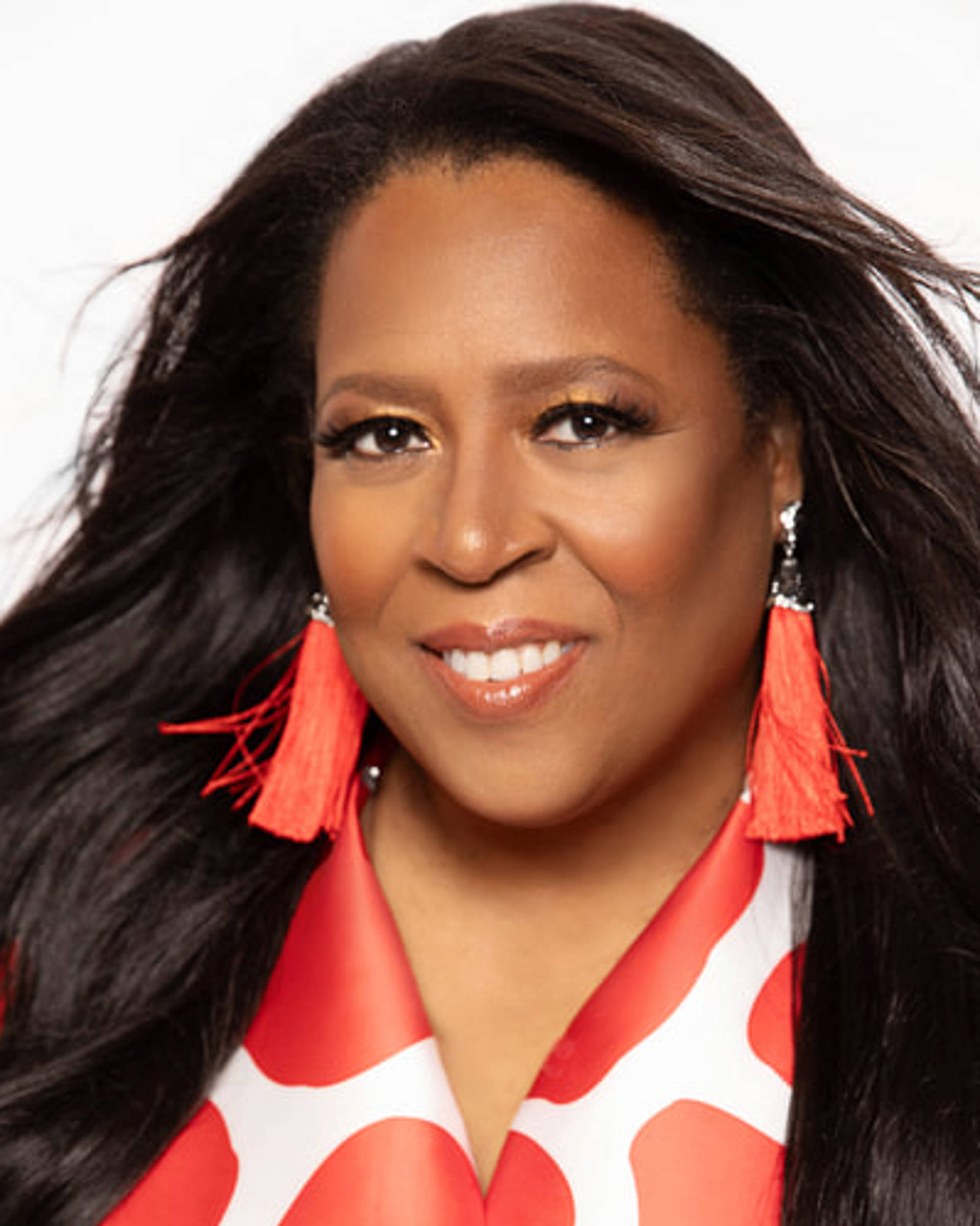 Headshot of an african american woman with long dark hair, red earings and a red and white top.