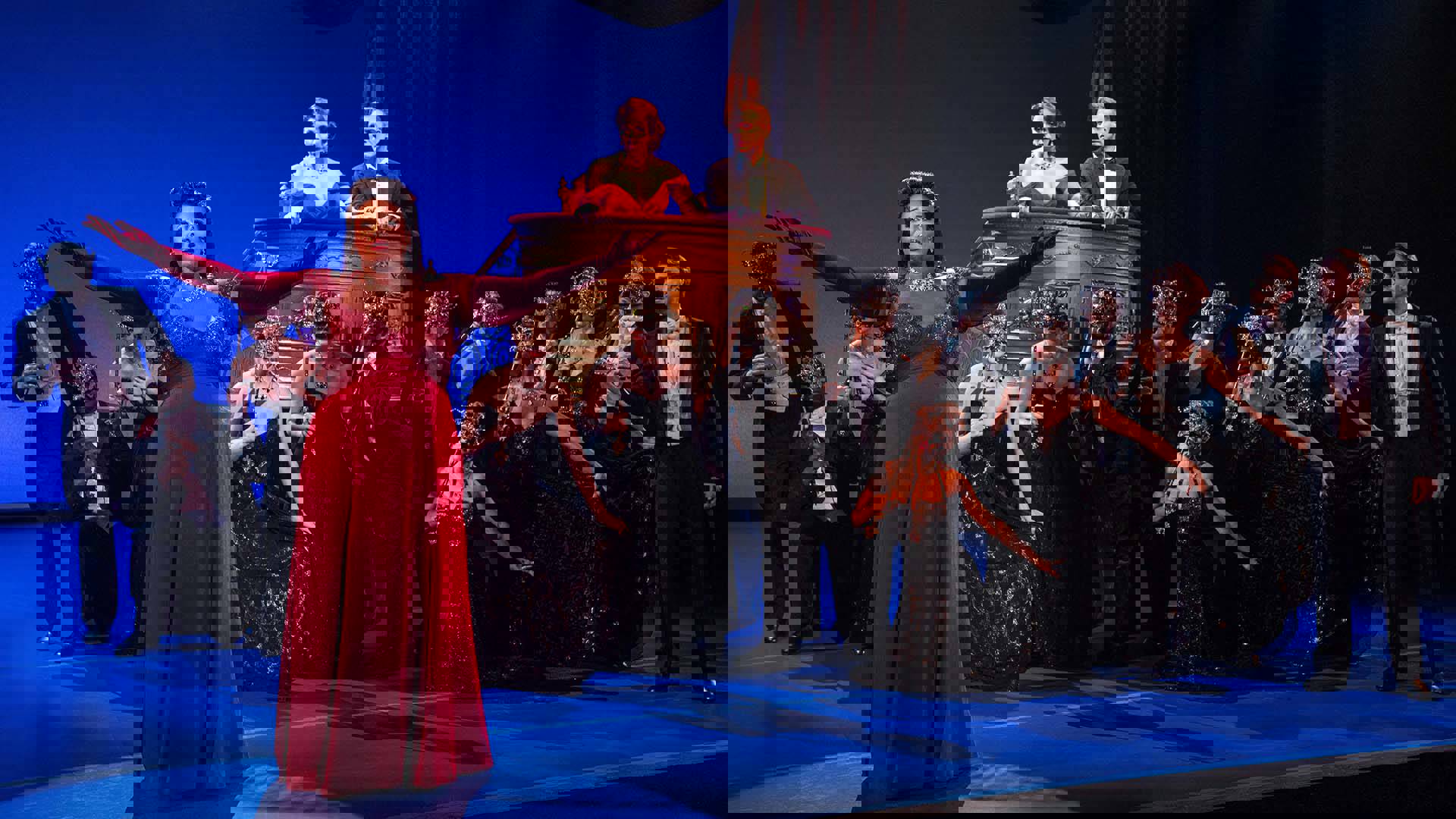 The Cast of Pretty Woman performing on stage. An African American woman in a beautiful red dress is singing with her arms outstretched.