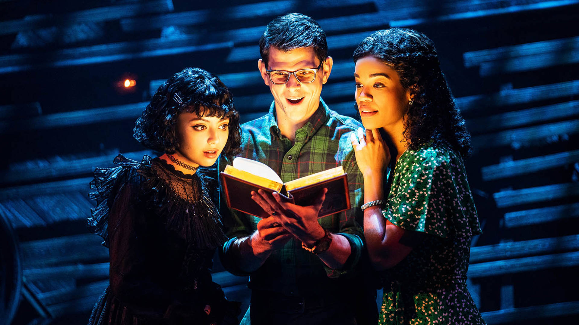 Three people standing close and staring into a glowing book with faces of wonder.