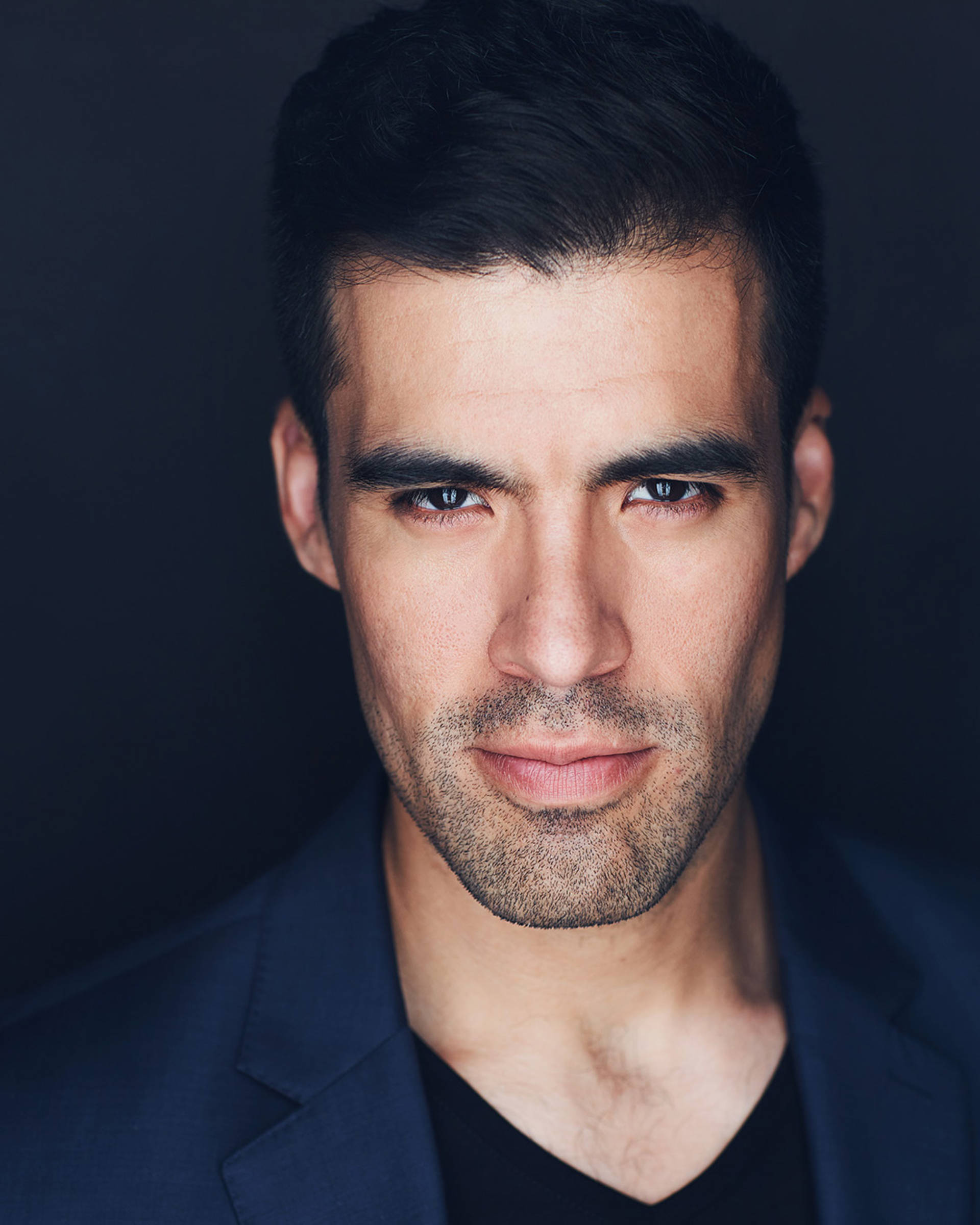 Heacshot of a man with medium complexions, dark short hair, dark eyes, and 5'oclock shadow.