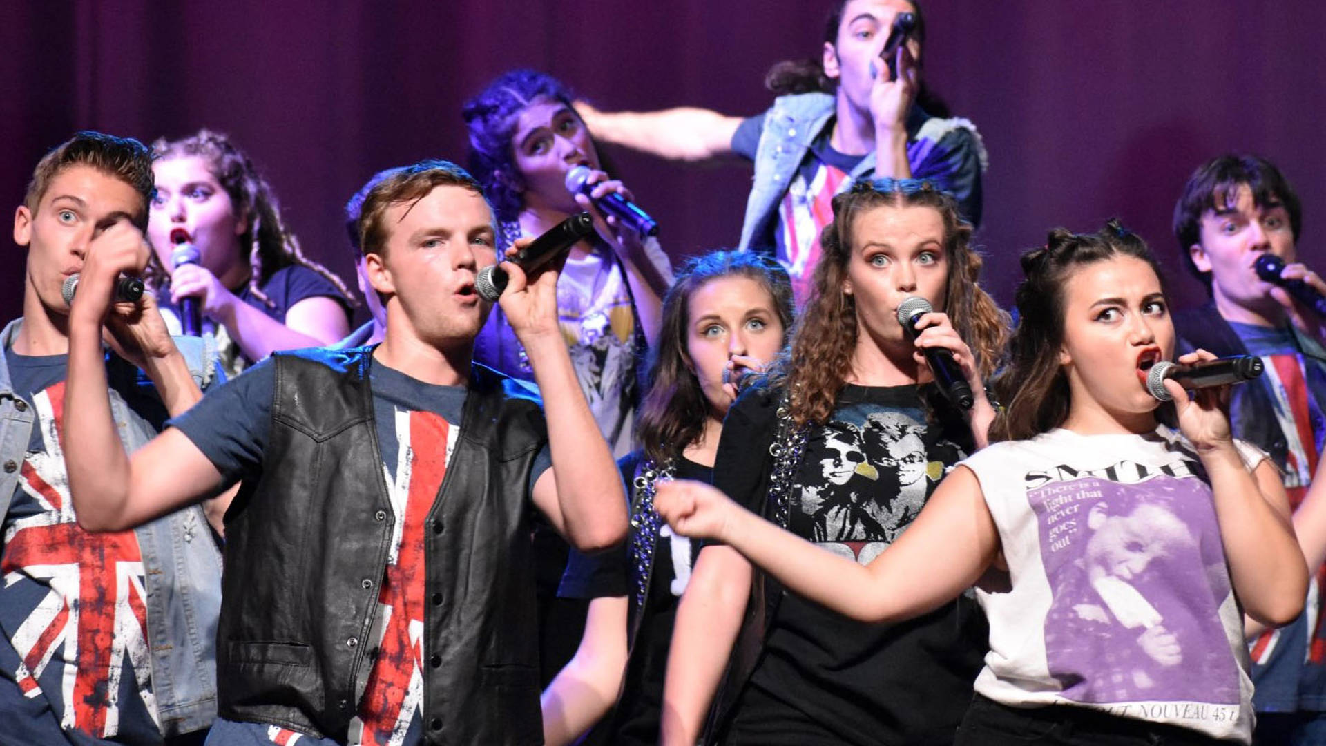 A group of high schoolers singing into microphones.