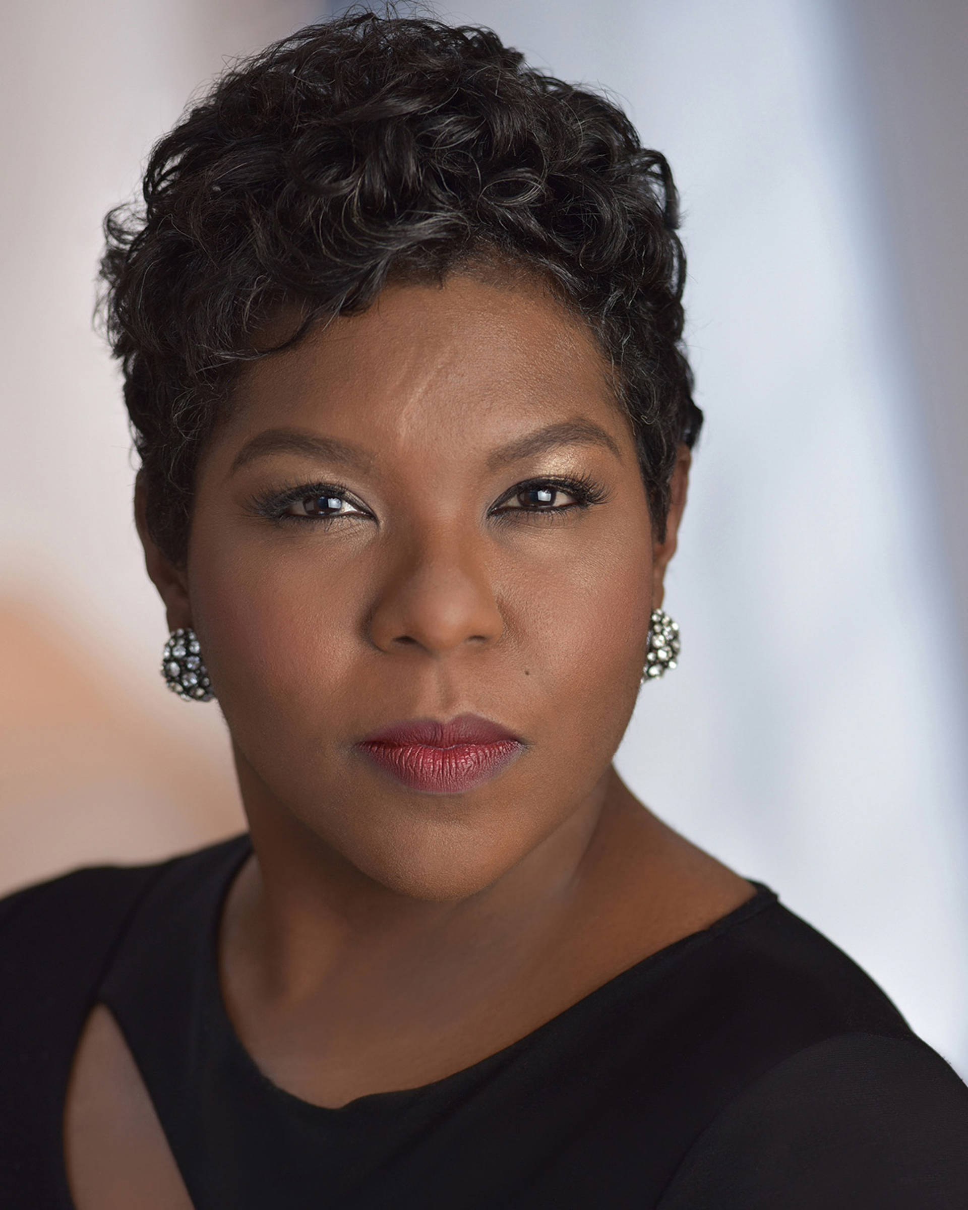 Headshot of an African American woman with short dark hair, brown eyes. and a black top.