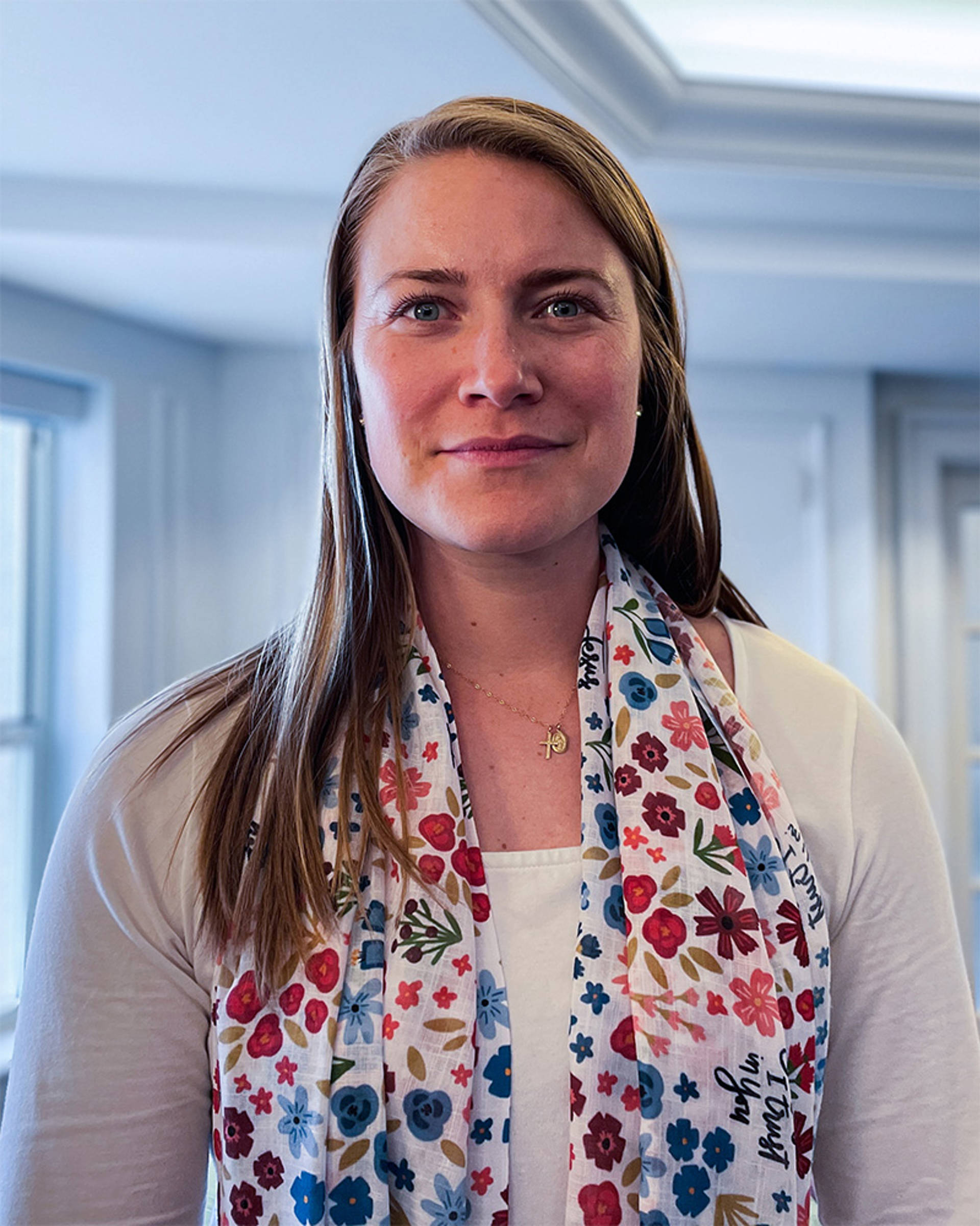 A young white woman with long brown hair in a white top.