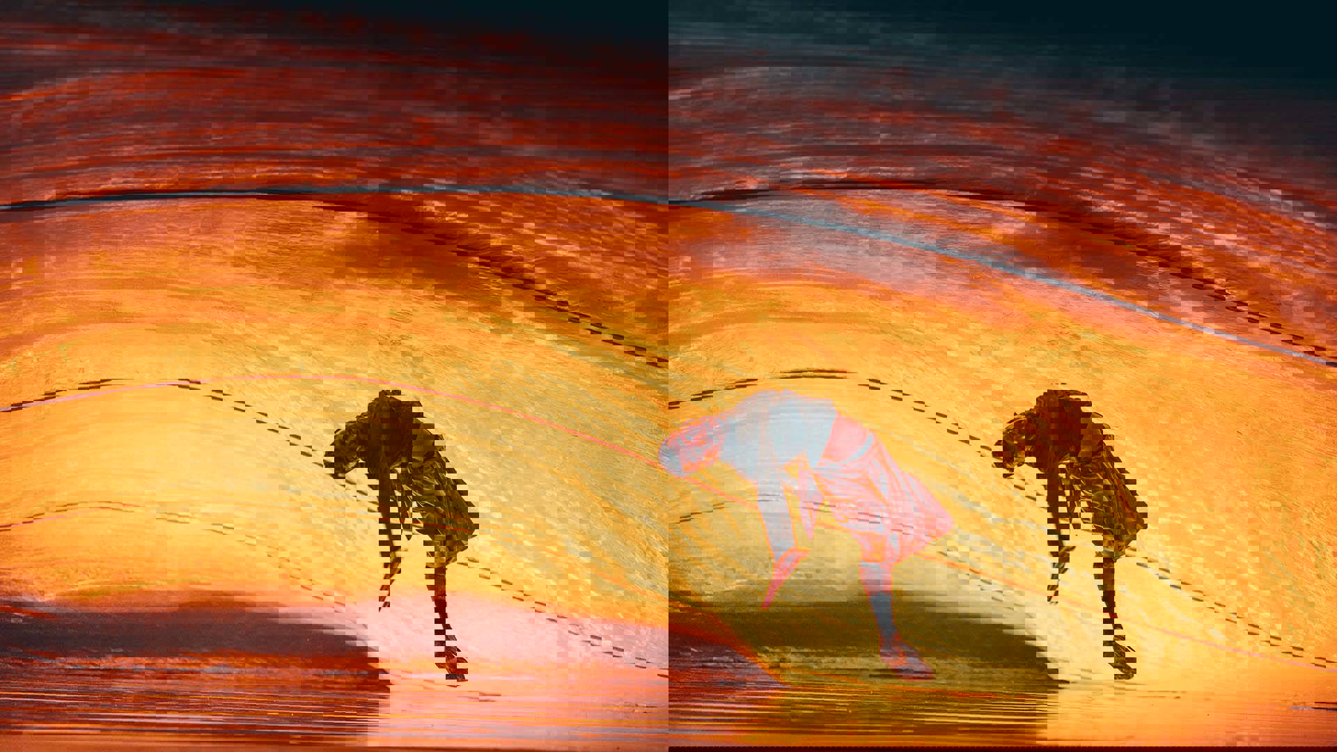 A dancer bending backwards with arms outstretched. A large golden fabric is moving behind him.