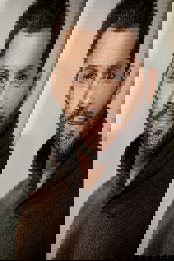 Headshot of Ryan Silverman. He has a handsome youthful face with short brown hair and brown eyes. He is wearing a brown sweater.