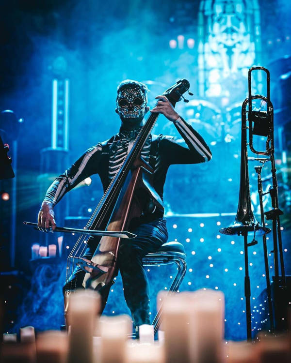 Person wearing a black skeleton costume and mask playing an electric cello.