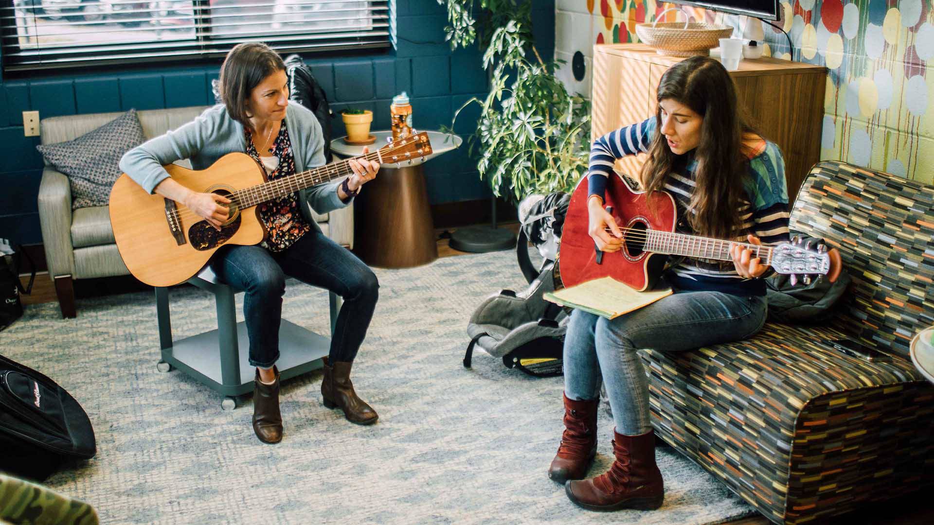 Two women playing guitars and singing. 