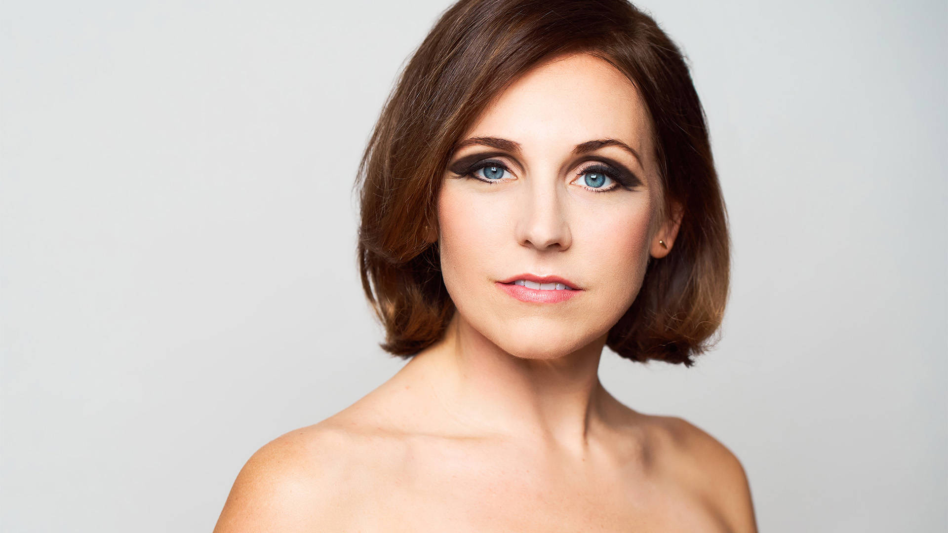 Headshot of a caucasian woman with medium brown hair and greenish blue eyes.