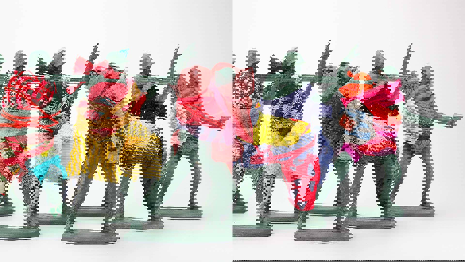Five green toy soldiers dressed in fabric scraps that bundle around their torsos.