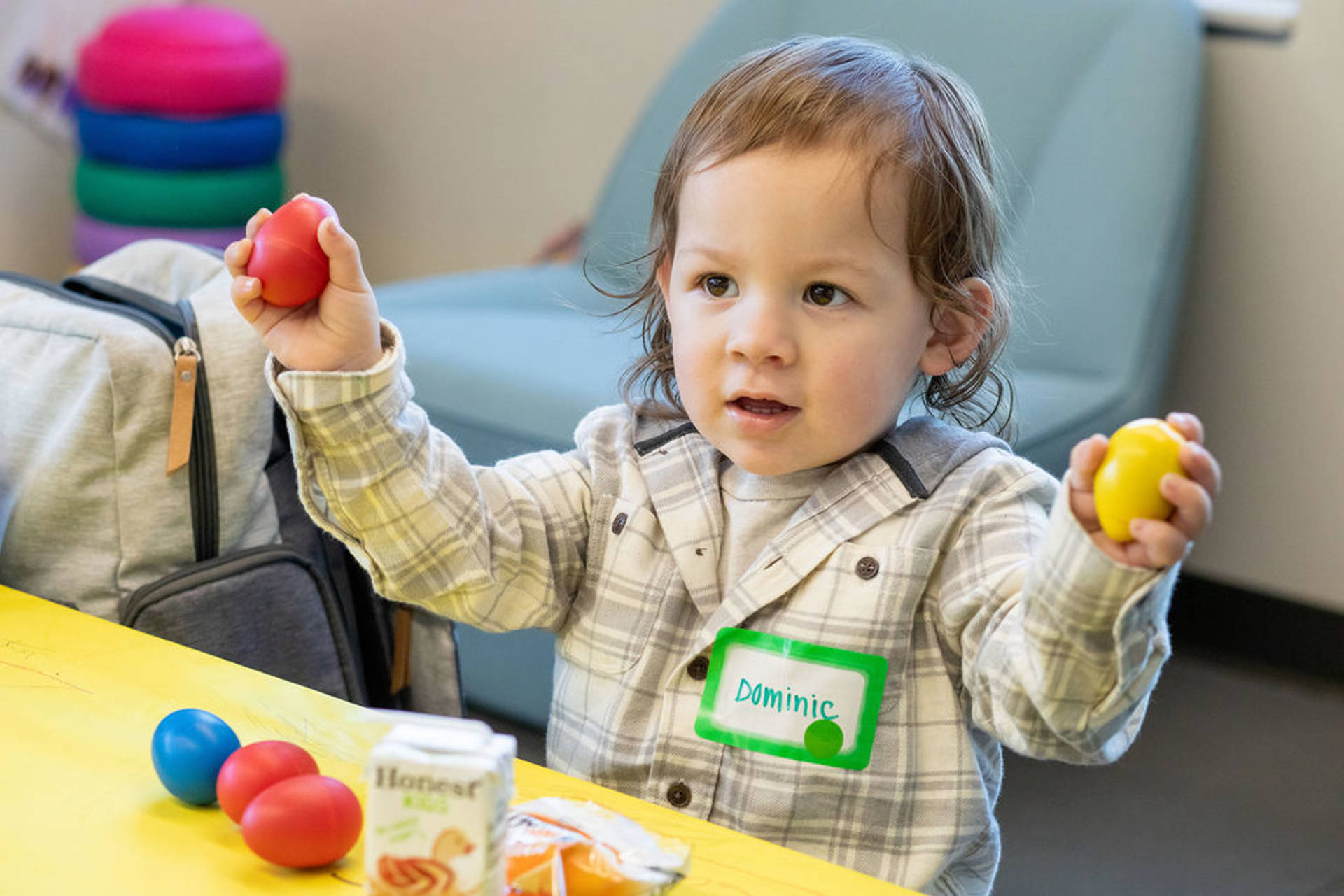 An toddler with light complexion and brown eyes holding two egg shakers.