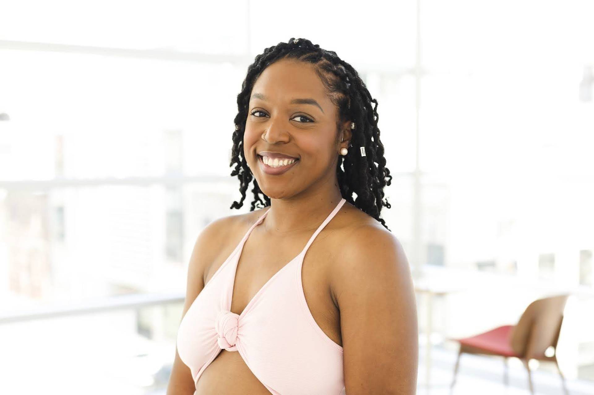 Headshot of a young woman with medium dark hair, dark complexion and brown eyes in a pink top.