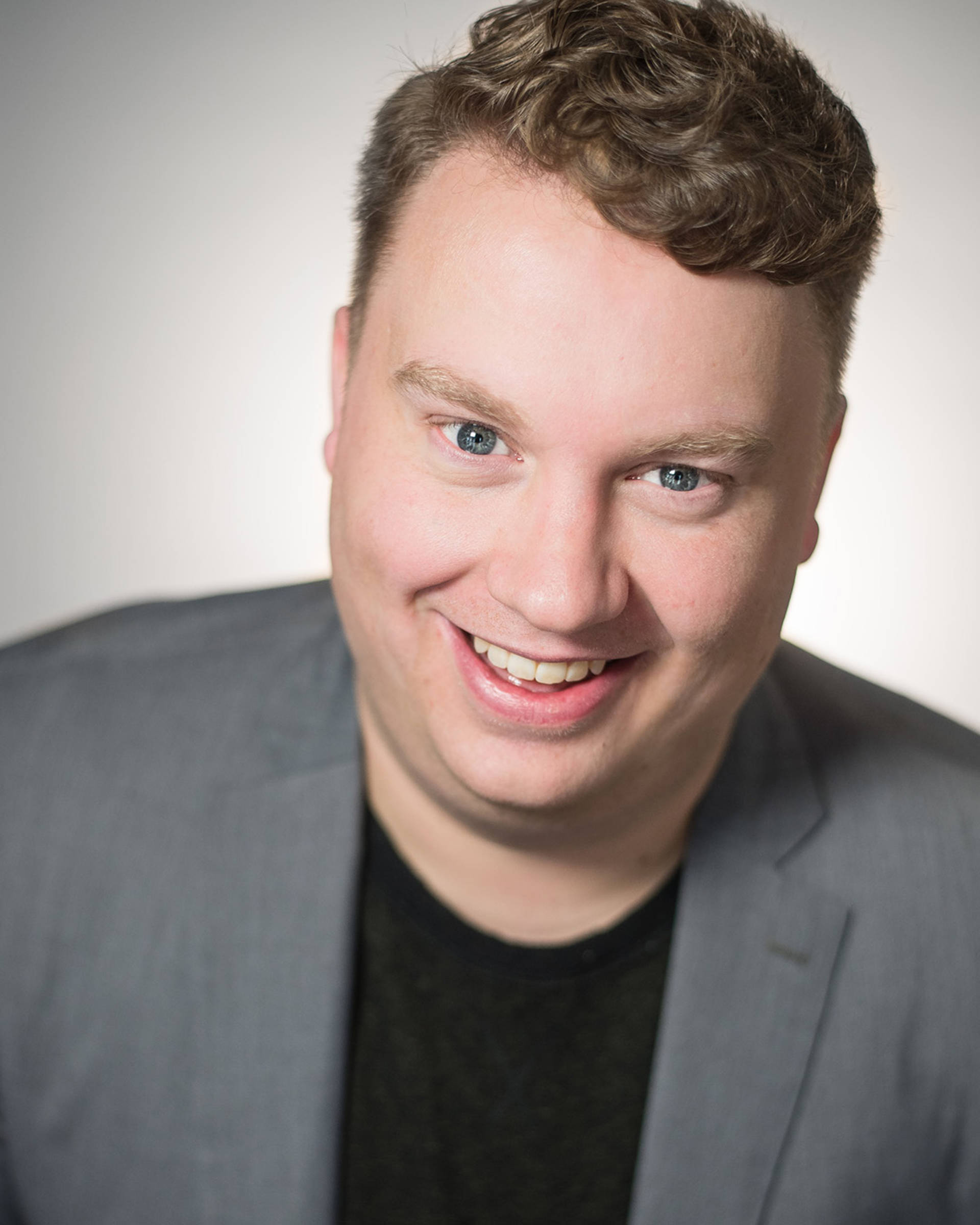 Headshot of a caucasian man with short dirty block hair, green eyes and a grey sportjacket.
