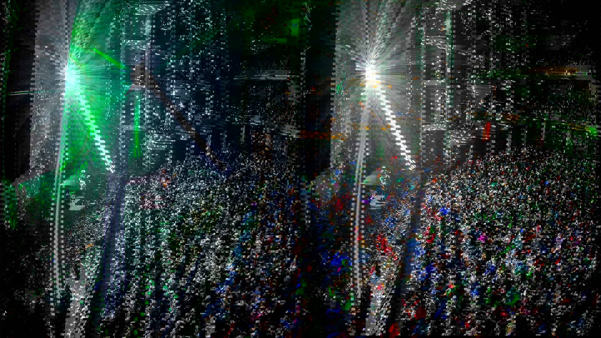 Side view of Brit Floyd band performing to a large seated audience. The stage lights are speckled and scattered across the theater.