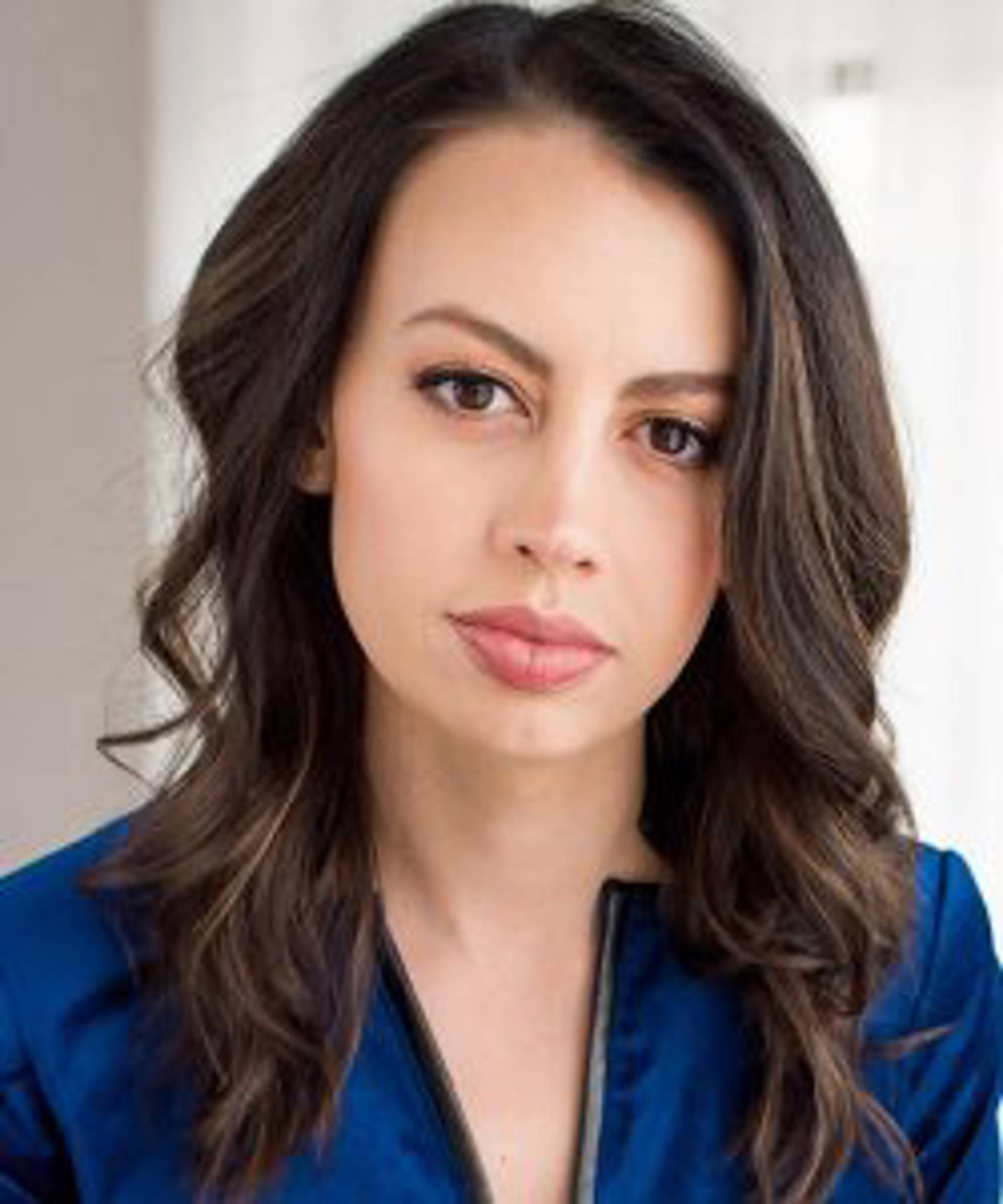 headshot of a woman with brown eyes and long brown hair in a blue top.
