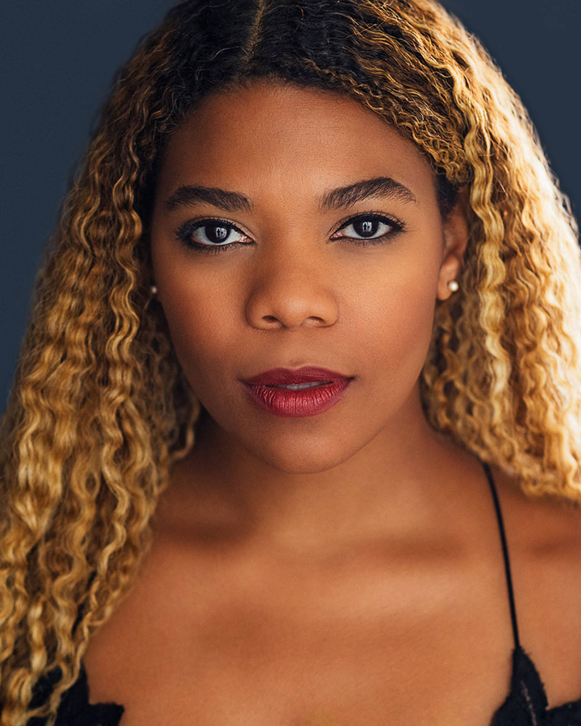 An African American woman with long wavy blonde hair in a black dress.