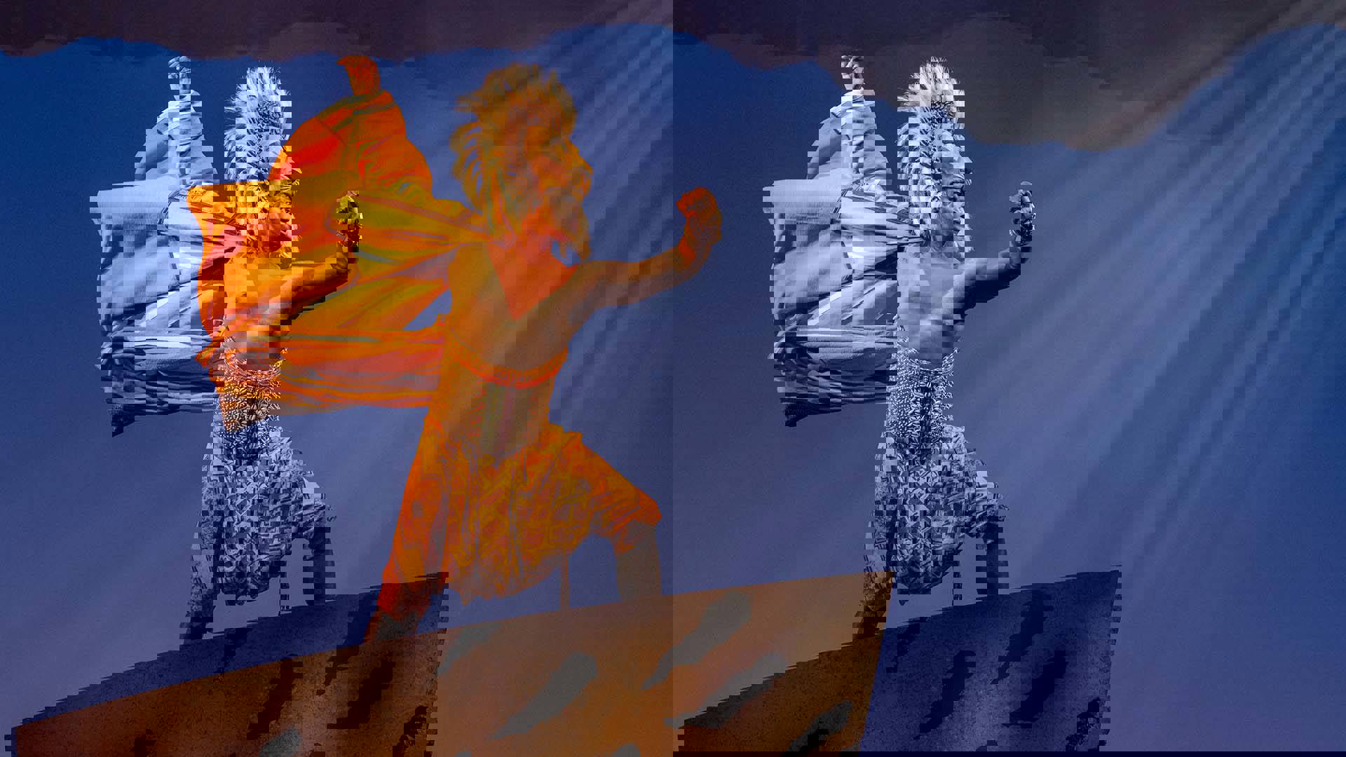 An actor dressed as Simba strikes a confident pose on an elevated platform