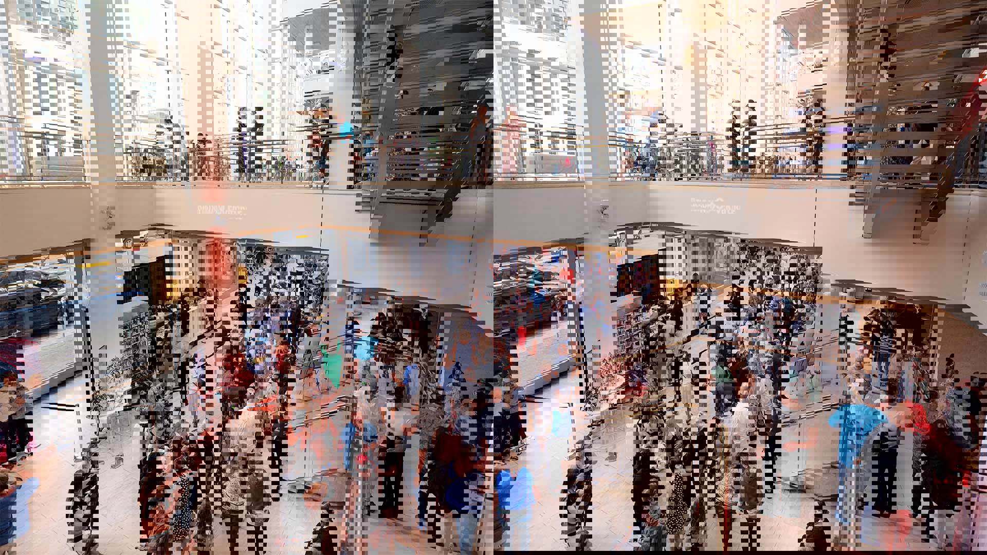 Overture Hall main lobby in daytime with a crowd of people moving through it and in line for concessions. Shows second level with people mingling before a Broadway show.