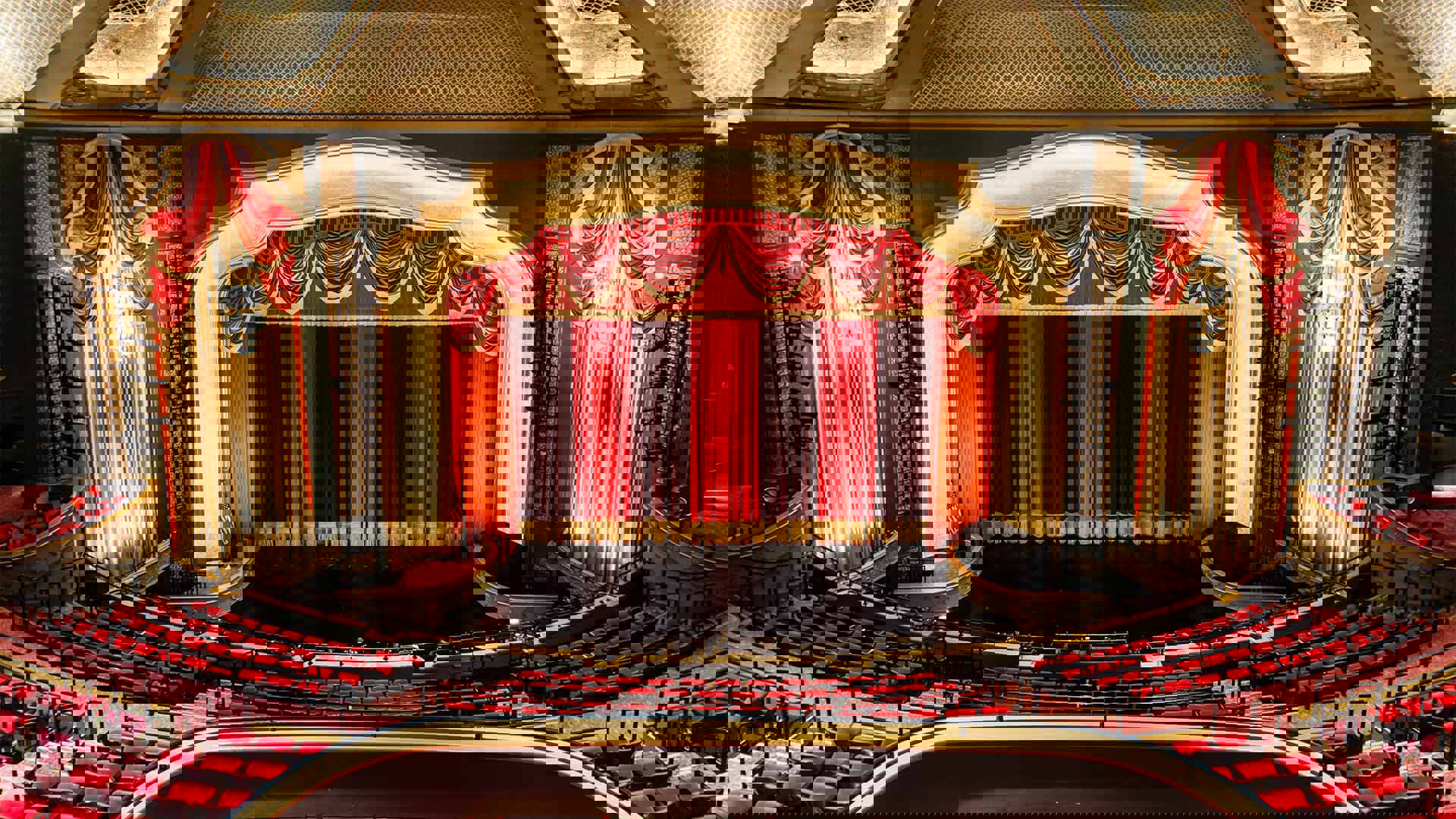 A wide view of Capitol Theater seats, stage and red curtain.