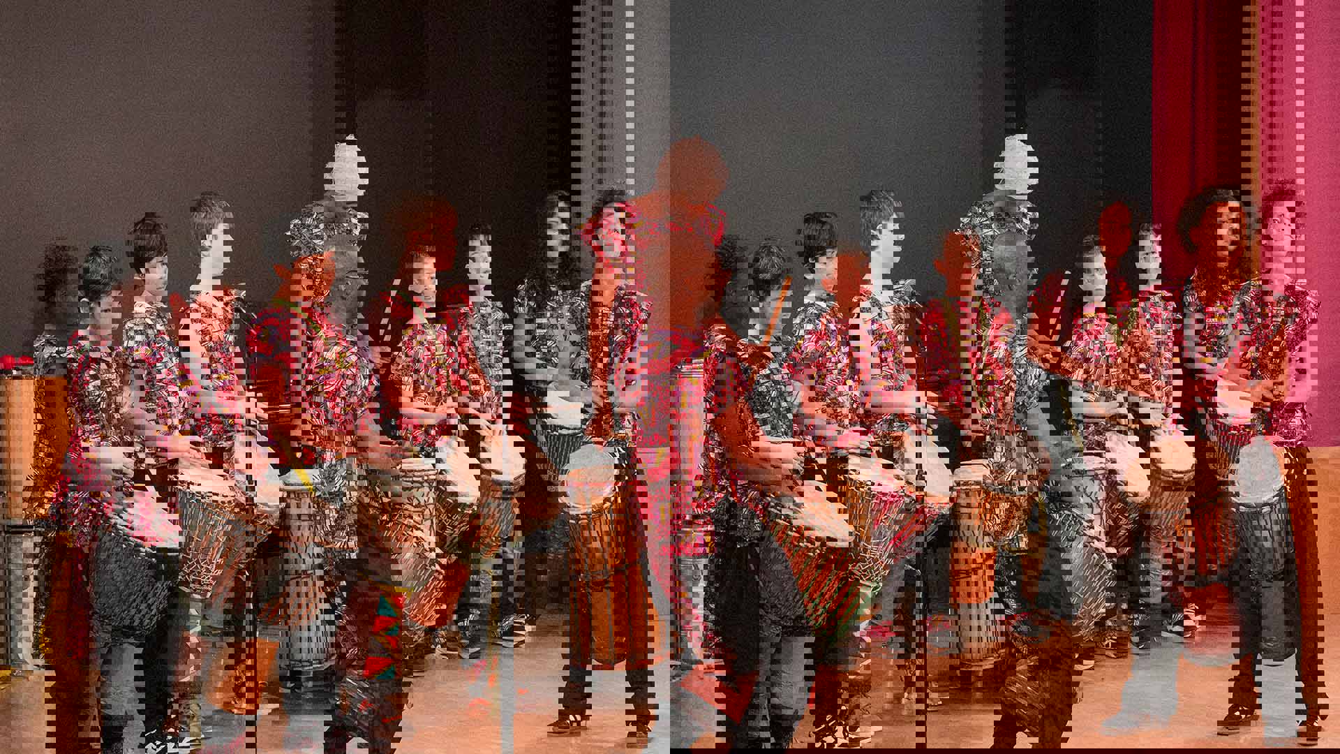 Group of children and two adult leaders performing as a drum group.