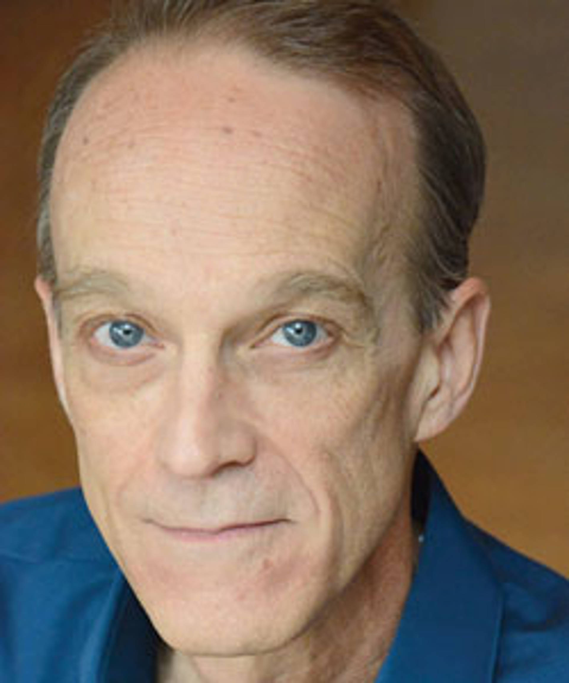 Headshot of a caucasian man with blue eyes and short fine light brown hair