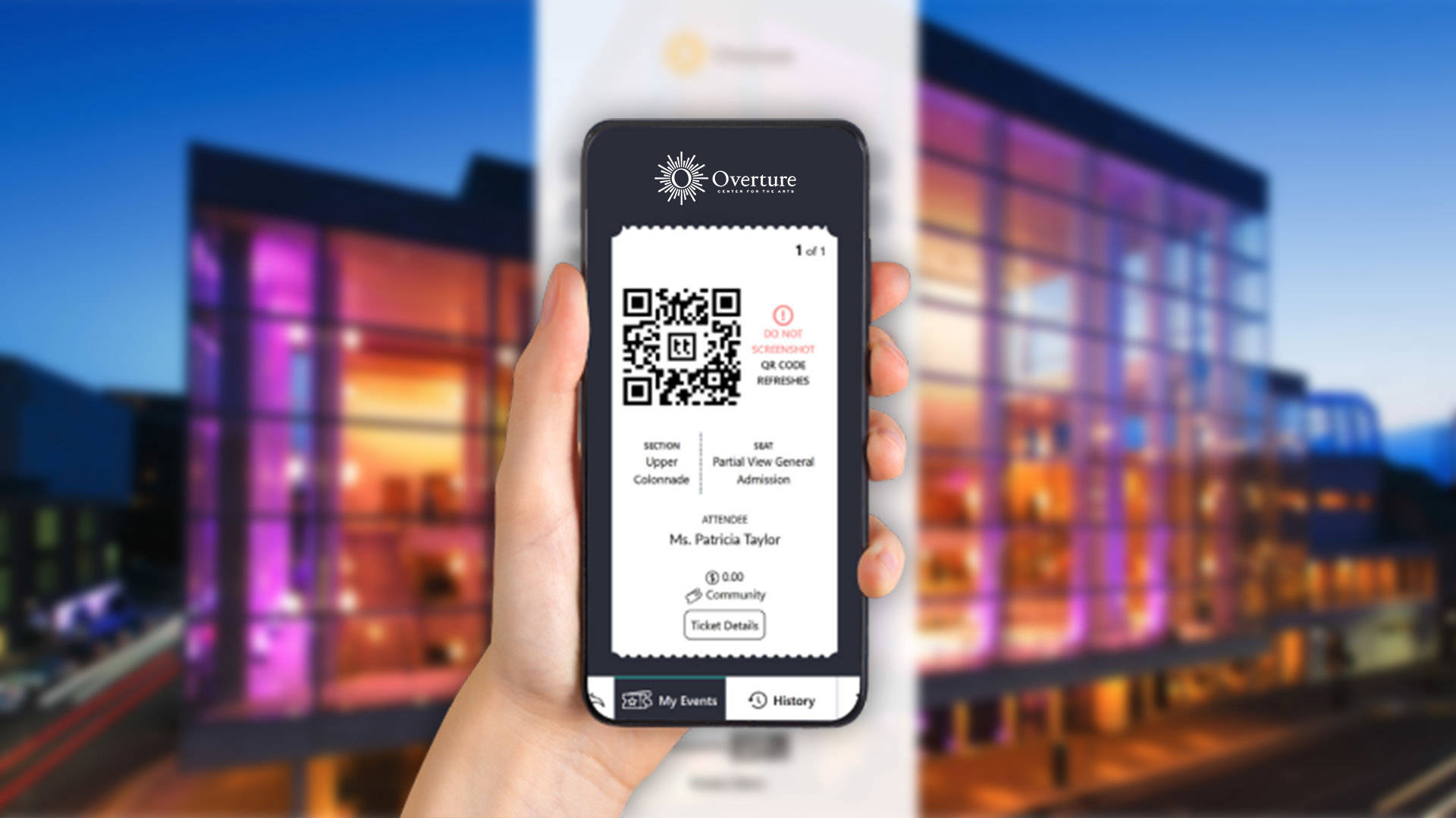 A hand holding a phone with a visible screen. On the screen is a QR code and several lines of personalized ticketing text. The background is a blury external view of Overture Center's glass facade.