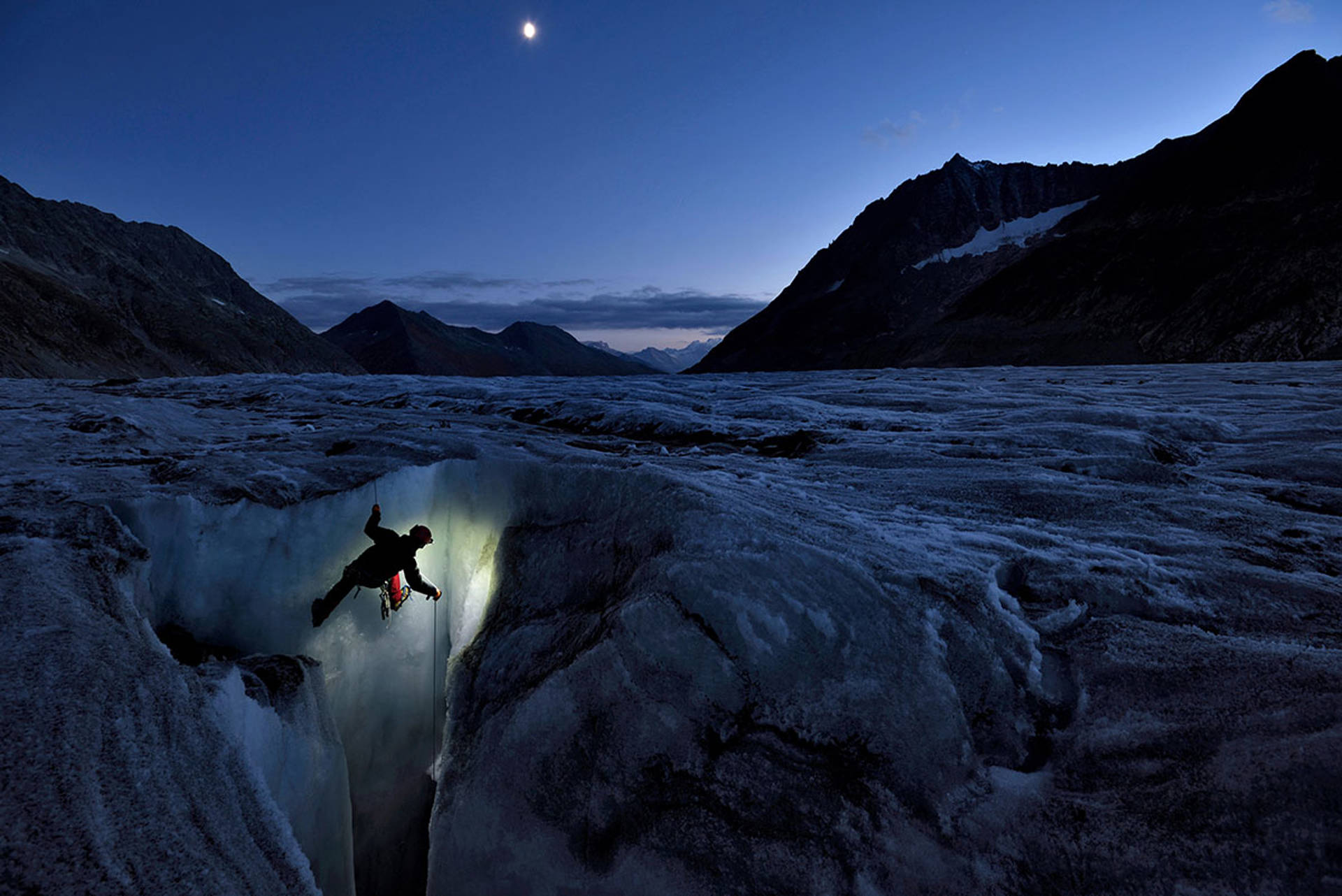 A Climber scales a glacier face in the dusk hours