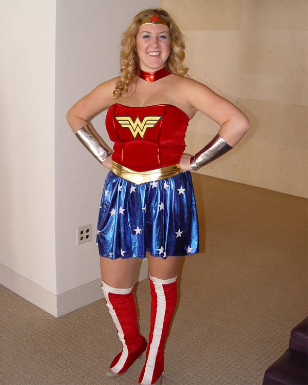 A caucasian woman with long blonde hair and blue eyes in a wonderwoman outfit.