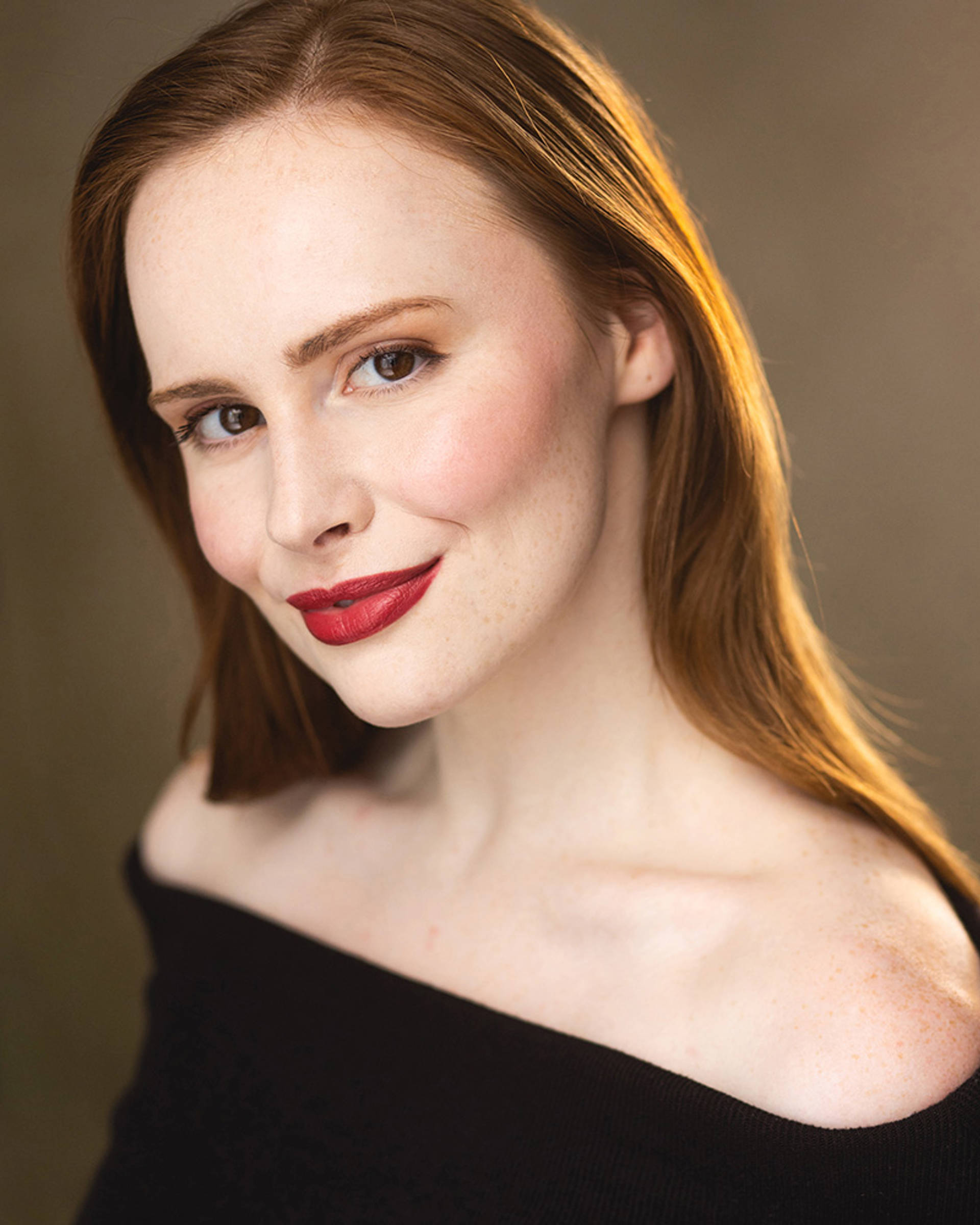 Headshot of a white woman with red hair, brown eyes and lipstick