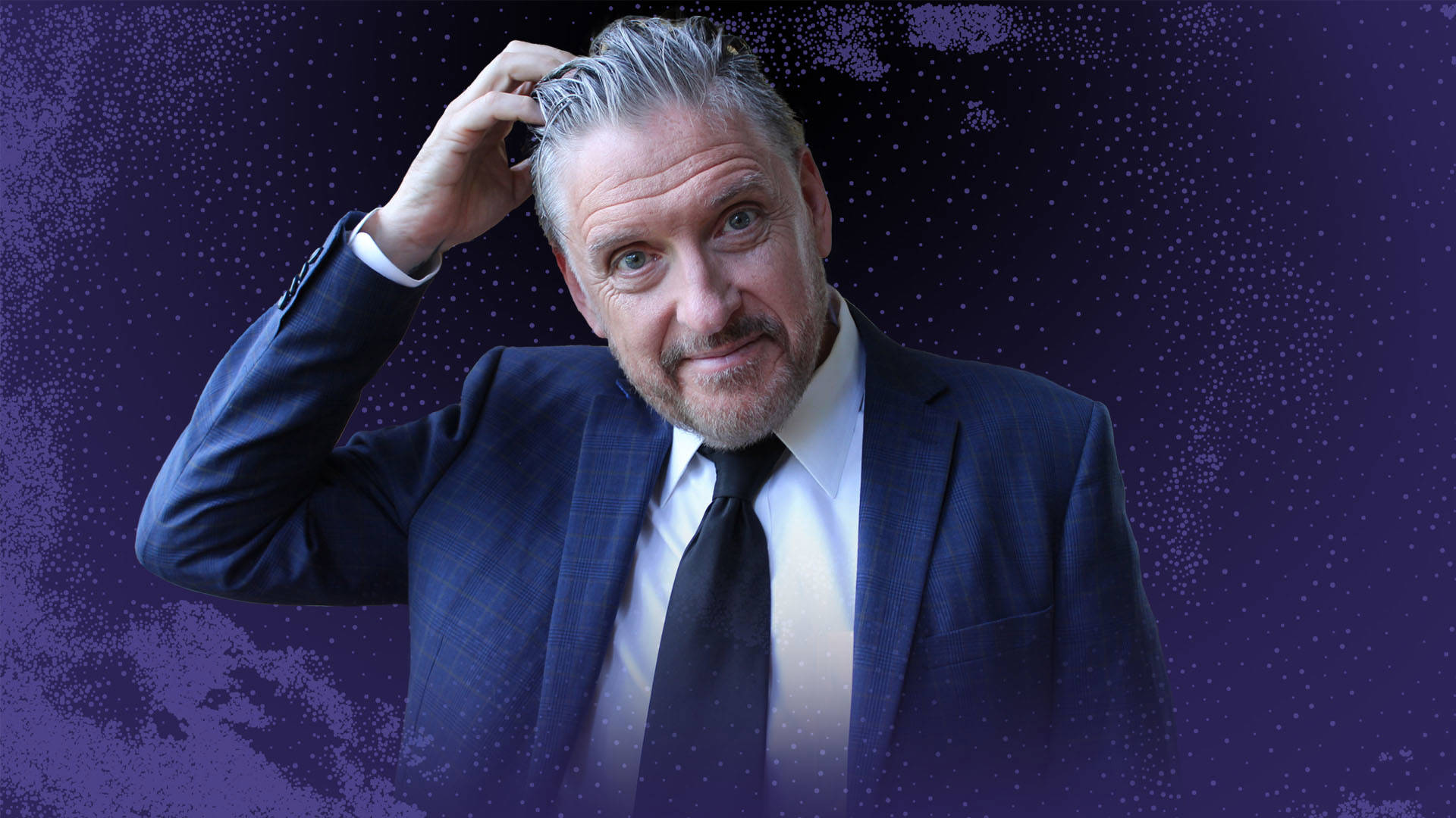 A middle-aged caucasian man in a suit with slicked back grey hair and 5-o-clock shadow scratches his head against a dark purple background. 